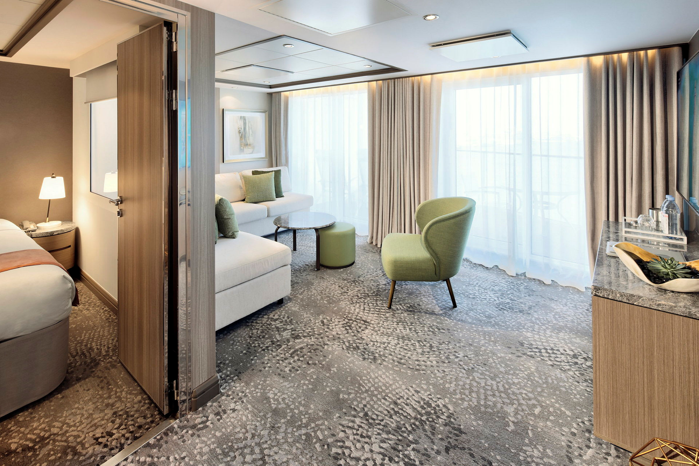 Hotelværelse med åbent område, sofa, lænestol og store vinduer. (AI-genereret tekst)