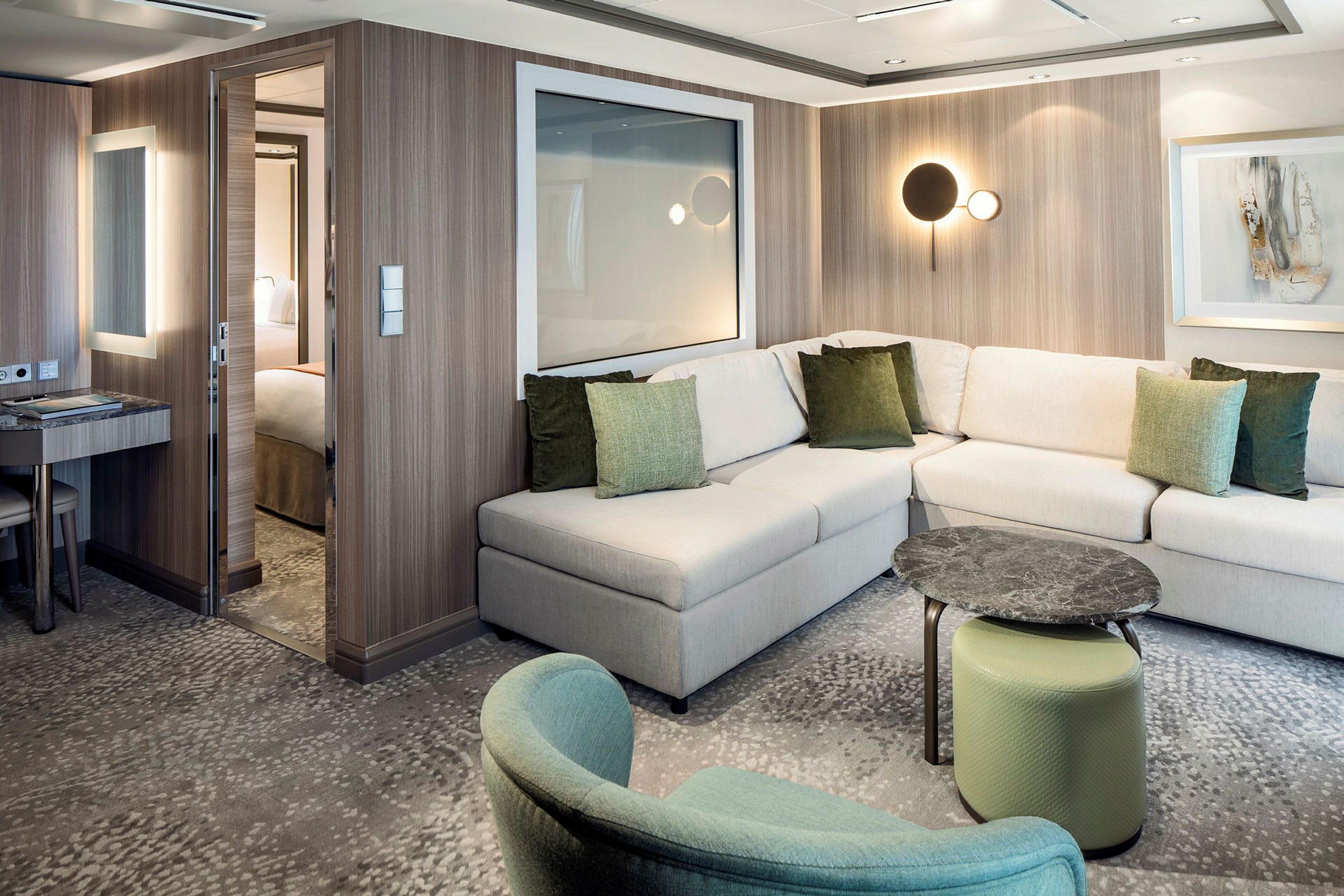 Et moderne hotelværelse med en L-formet sofa, grønne puder, et lille bord og en siddeindretning. (AI-genereret tekst)