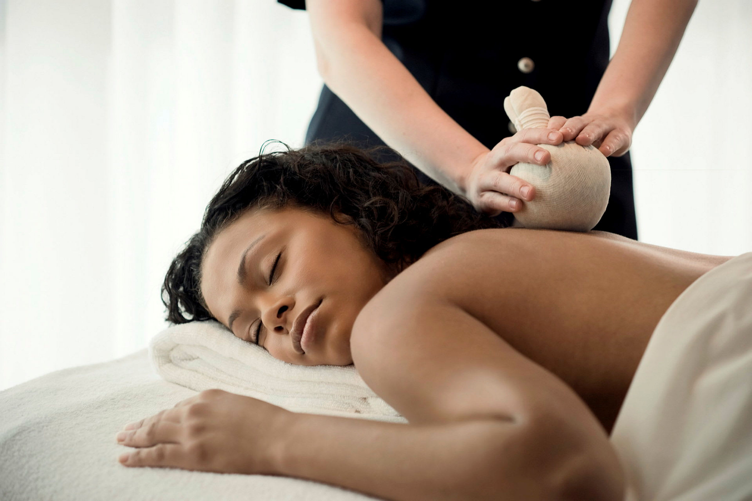 Person modtager massage med en urtepose. (AI-genereret tekst)