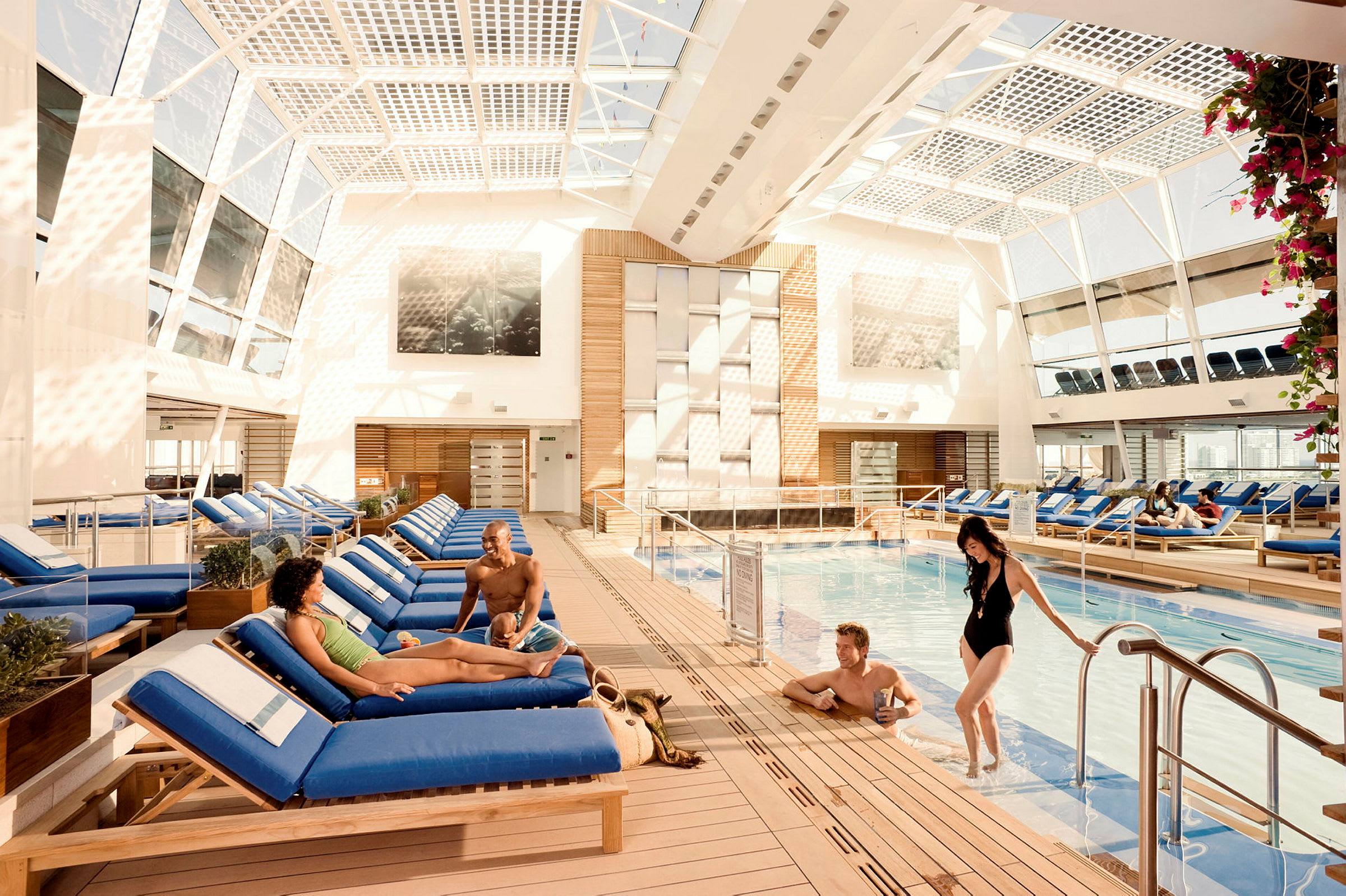 En indendørs pool omgivet af liggestole og lys arkitektur. (AI-genereret tekst)