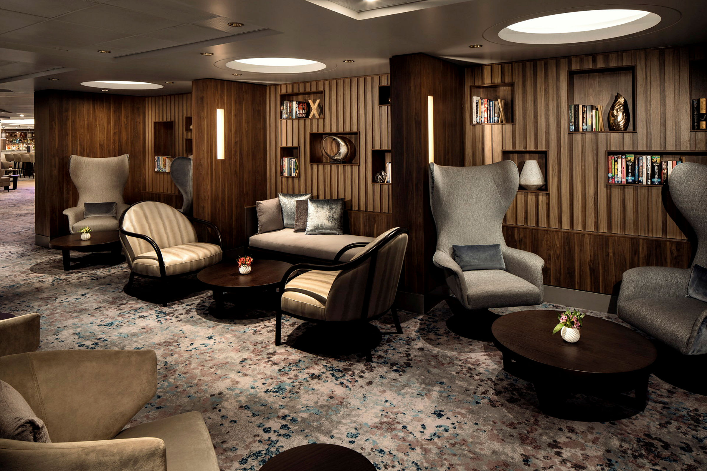 En elegant lounge med siddegrupper og boghylder. (AI-genereret tekst)