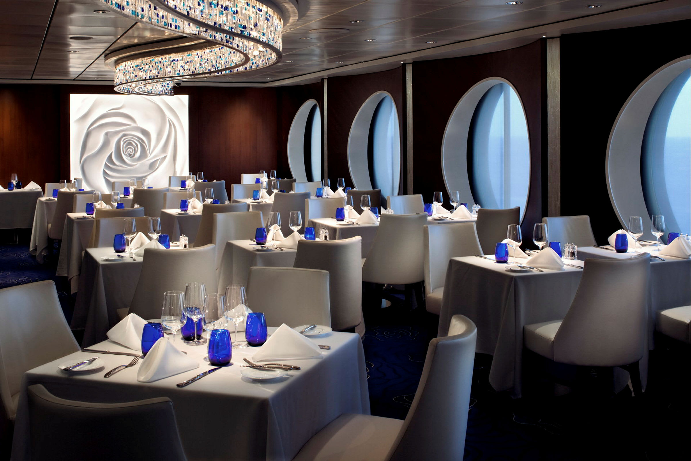 En elegant restaurant med hvide duge, blå glas og moderne stole. (AI-genereret tekst)
