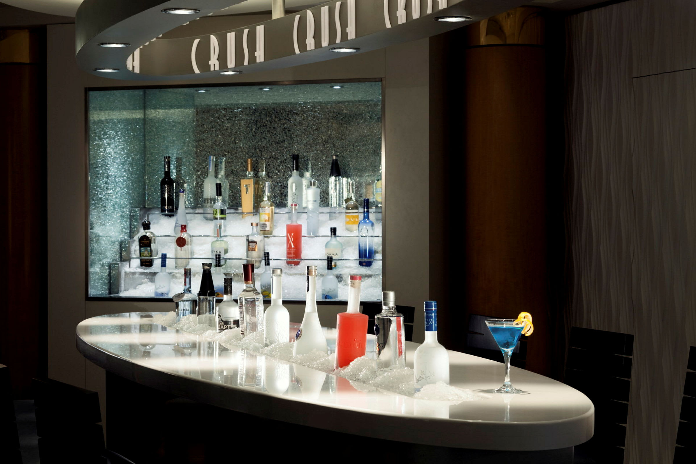 Bar med en række alkoholflasker på is, samt en blå cocktail. (AI-genereret tekst)