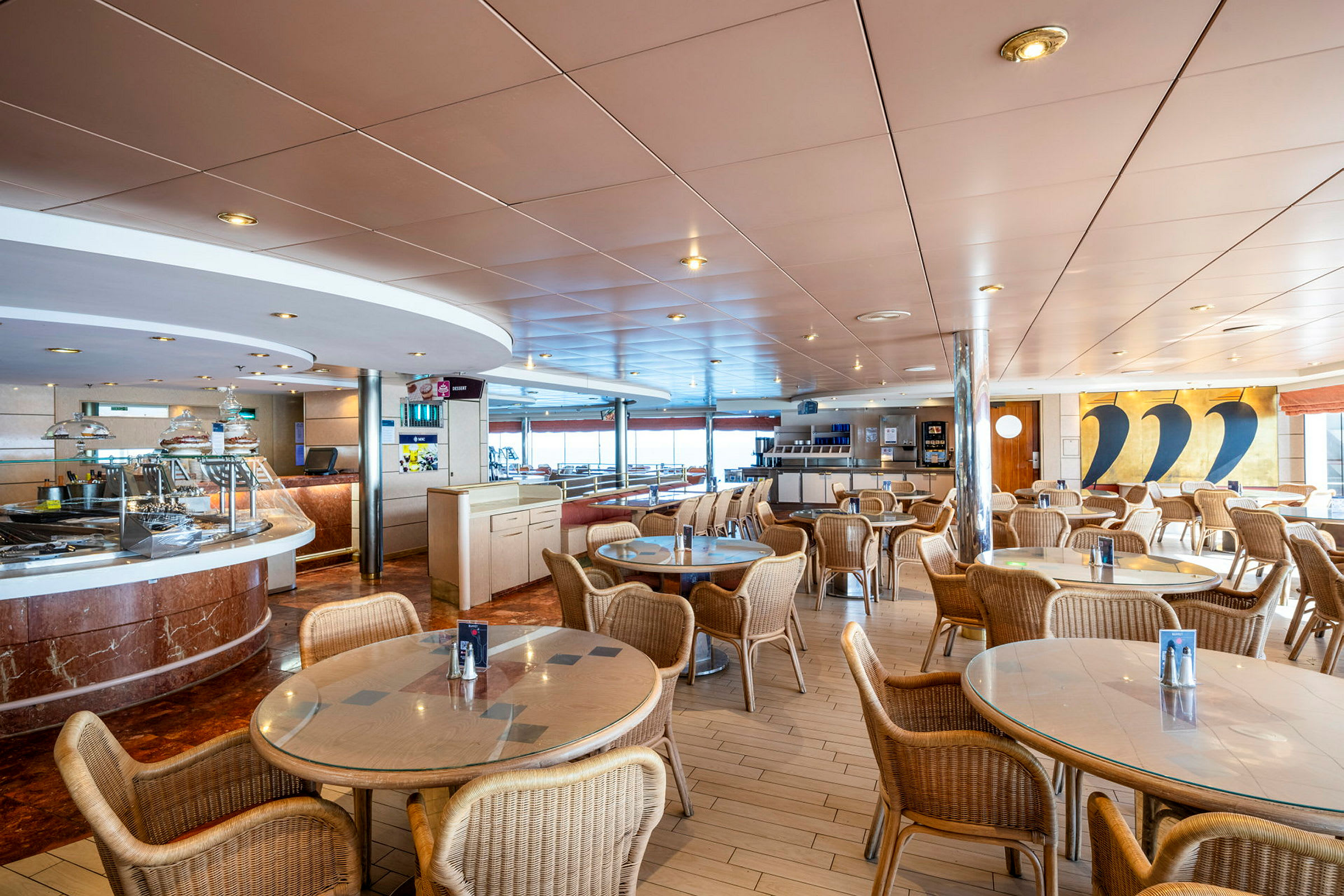 Interiør af en restaurant med klare farver, runde borde og kurvestole. (AI-genereret tekst)