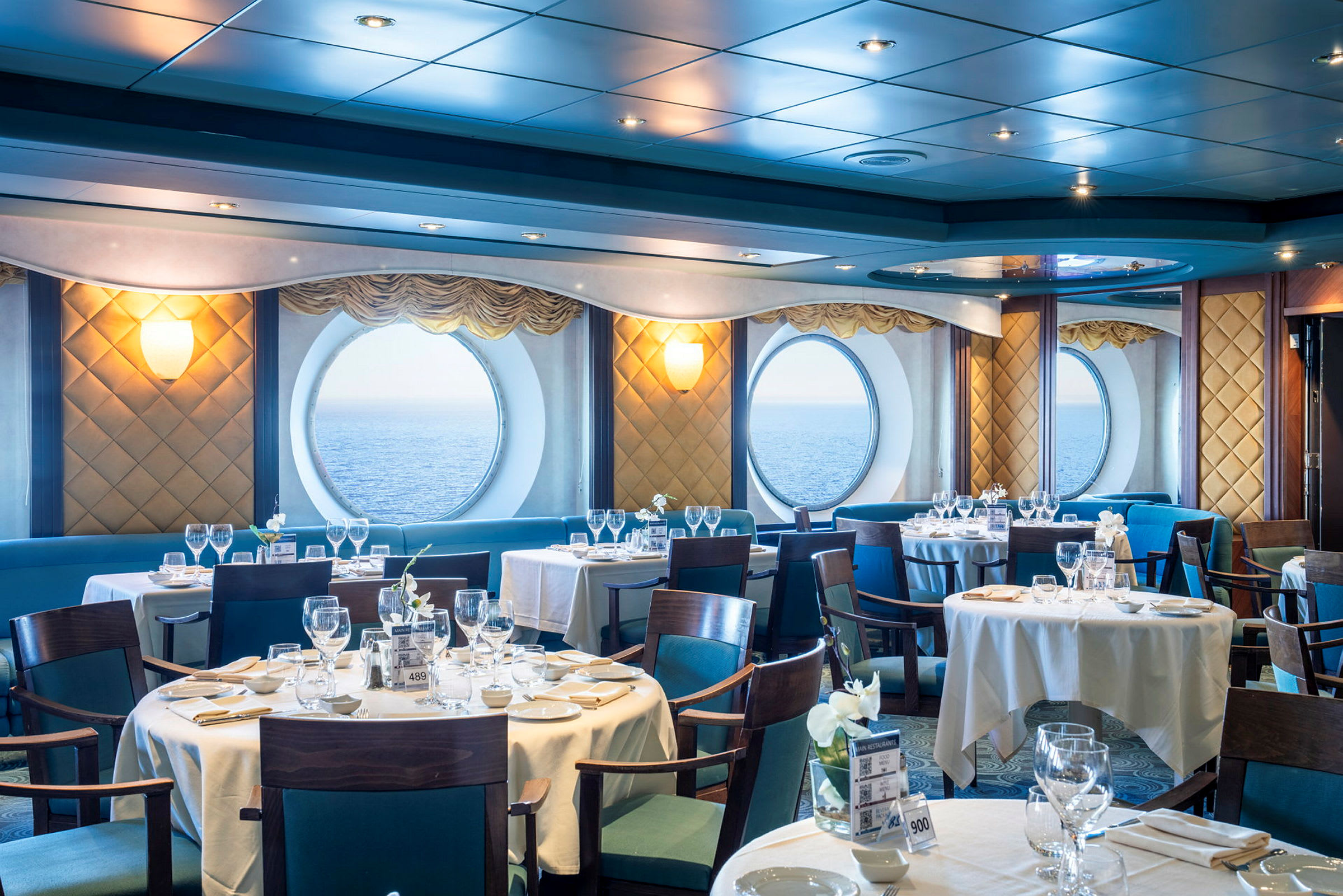 Restaurant med dækkede borde, store vinduer med havudsigt. (AI-genereret tekst)