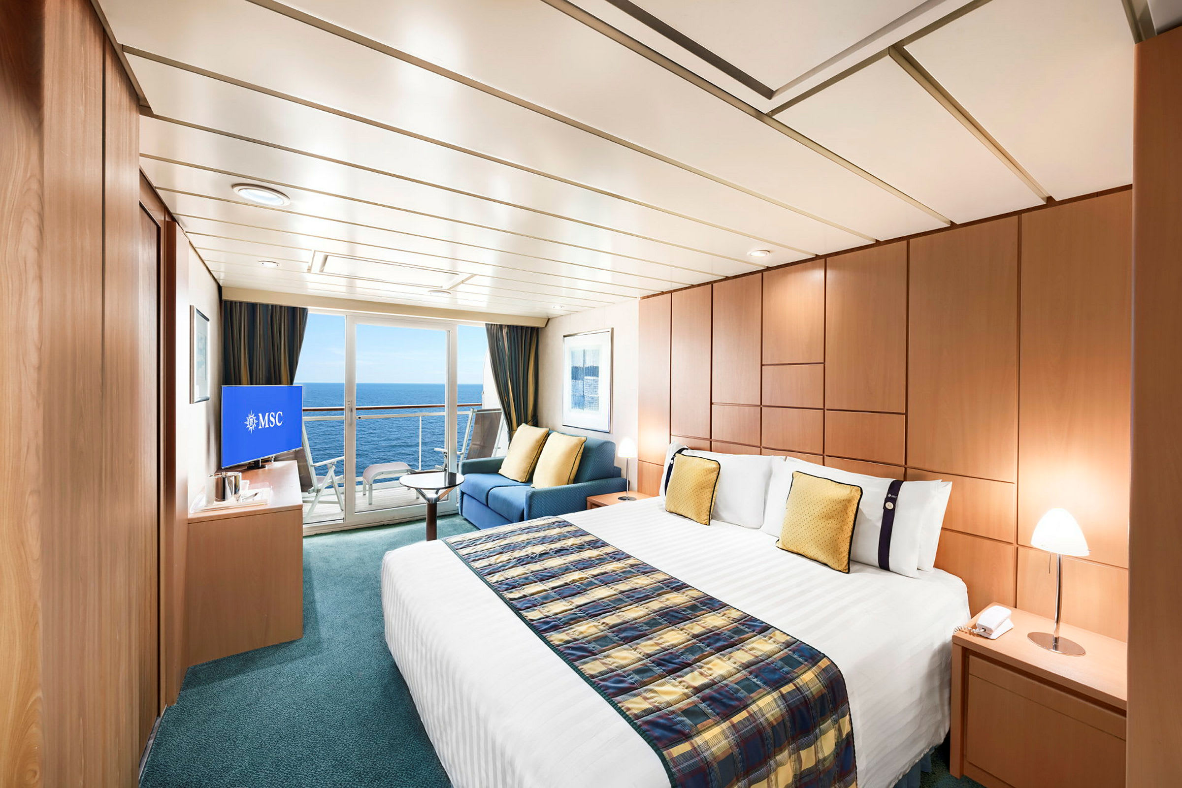 Billede af et rummeligt og elegant indrettet hotelværelse med stor seng, siddeområde og havudsigt gennem glasdøre. (AI-genereret tekst)