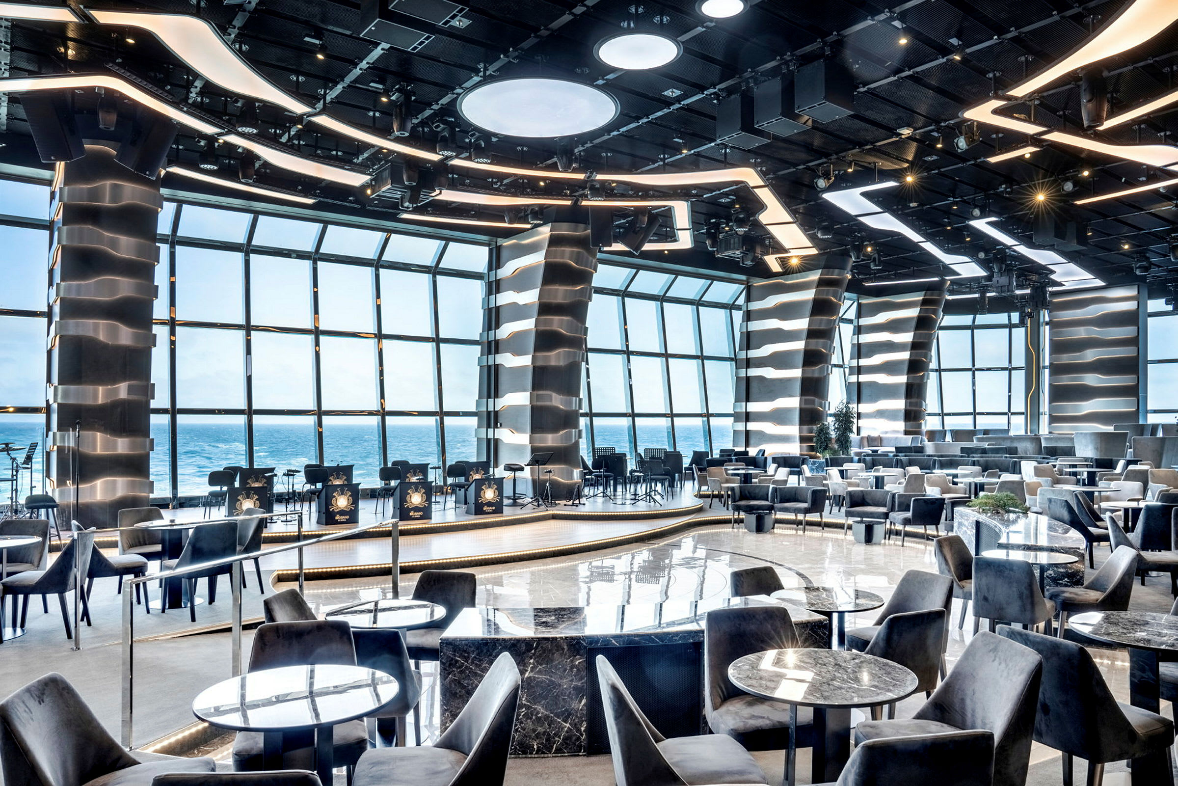 Restaurantmiljø med moderne design og havudsigt gennem store vinduer. (AI-genereret tekst)
