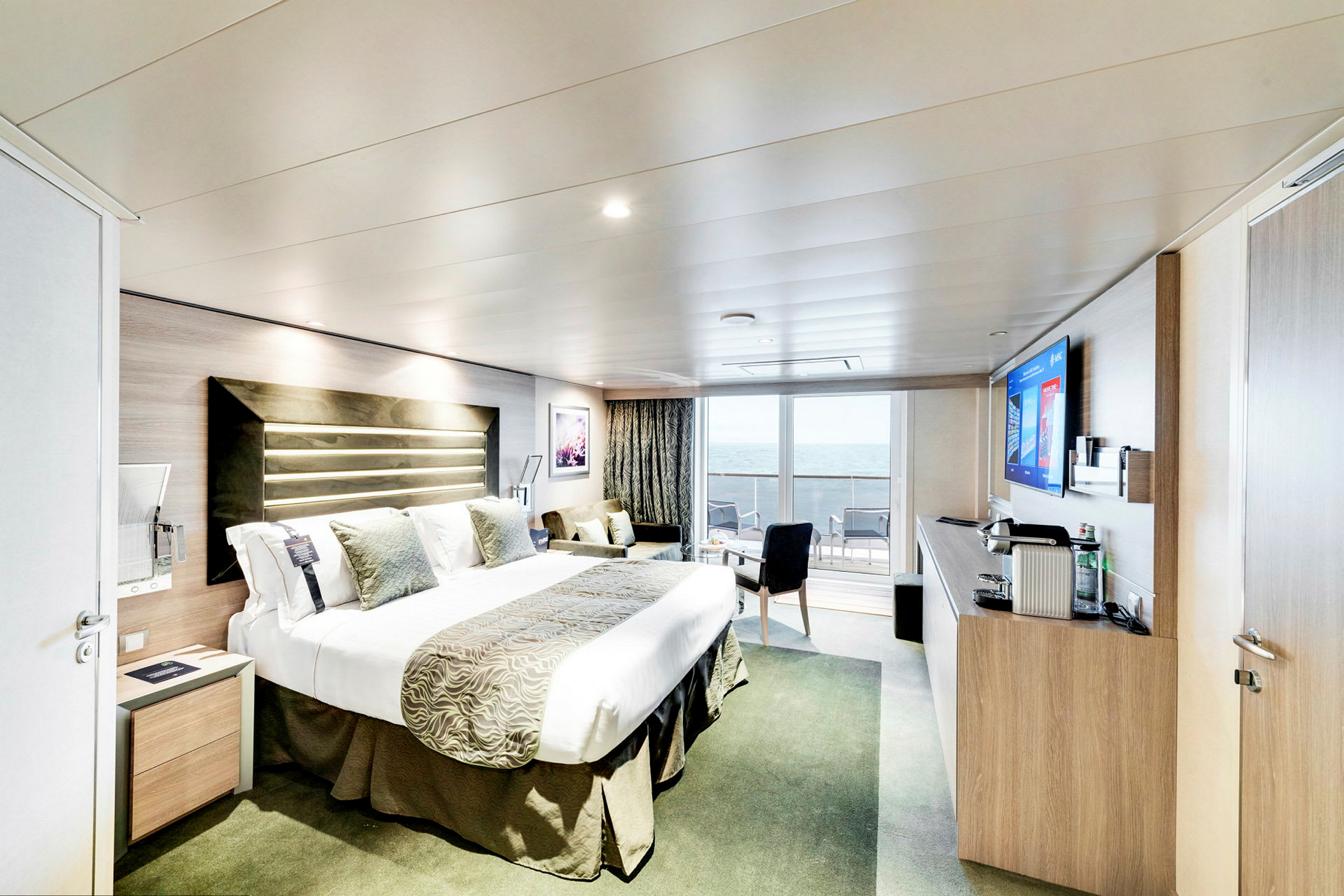 Hotelværelse med dobbeltseng og udsigt over havet fra altanen. (AI-genereret tekst)