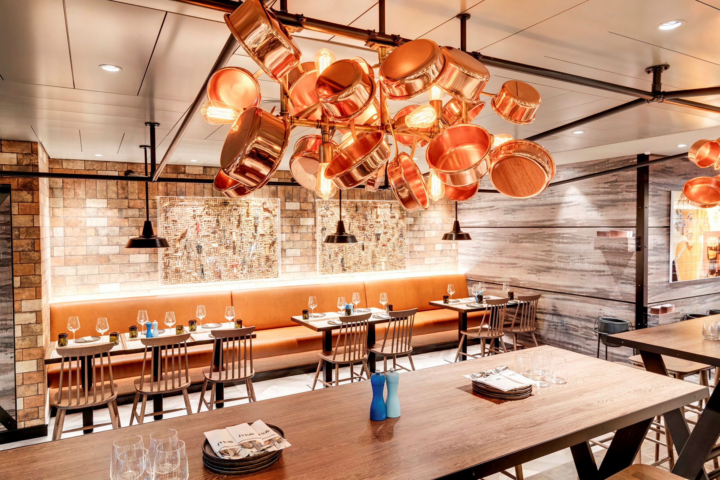 Restaurant med træborde, stole og loftlampe af kobberkar. (AI-genereret tekst)