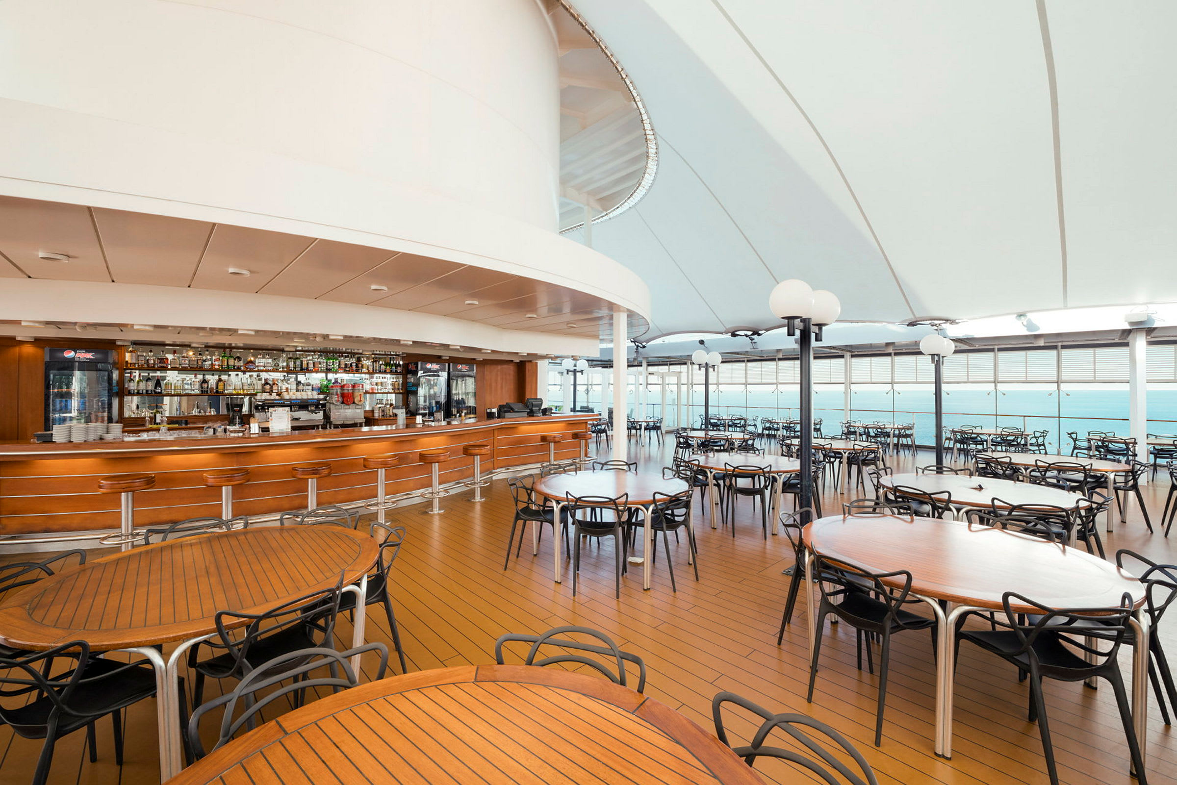 En overdækket restaurant med træborde, stole og en bar. (AI-genereret tekst)