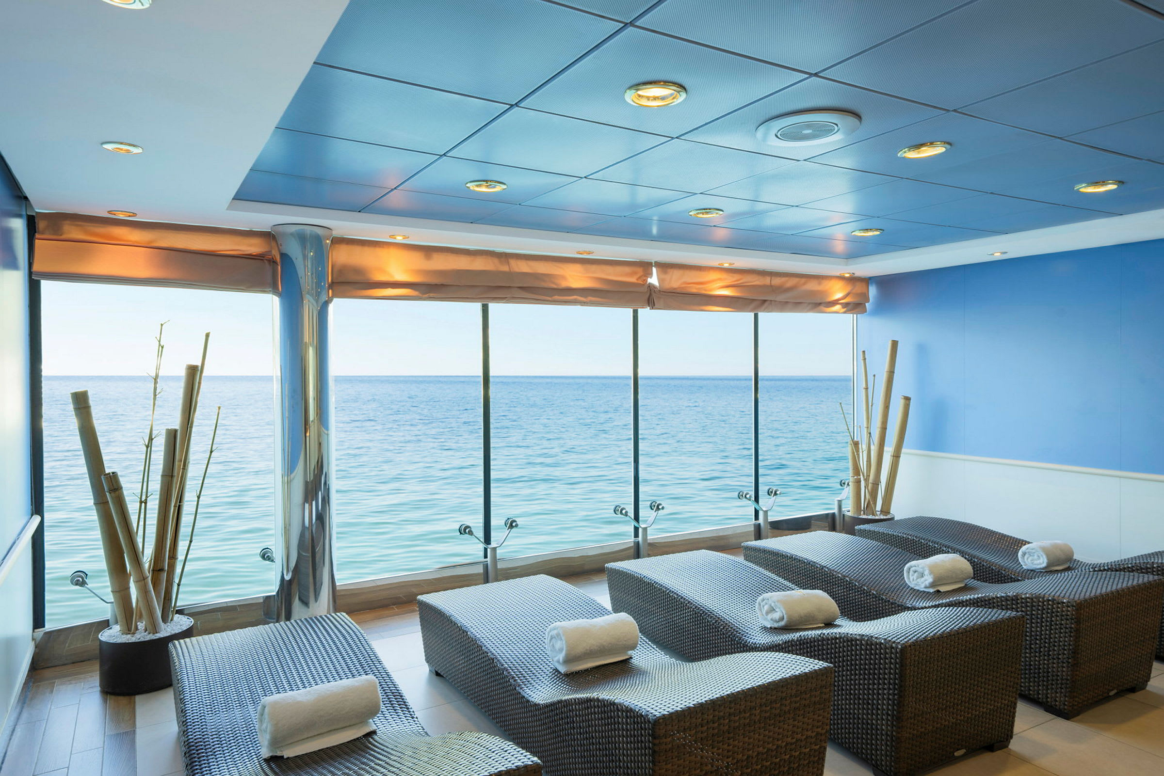 Spa-lounge med udsigt over havet, liggestole beklædt med håndklæder. (AI-genereret tekst)