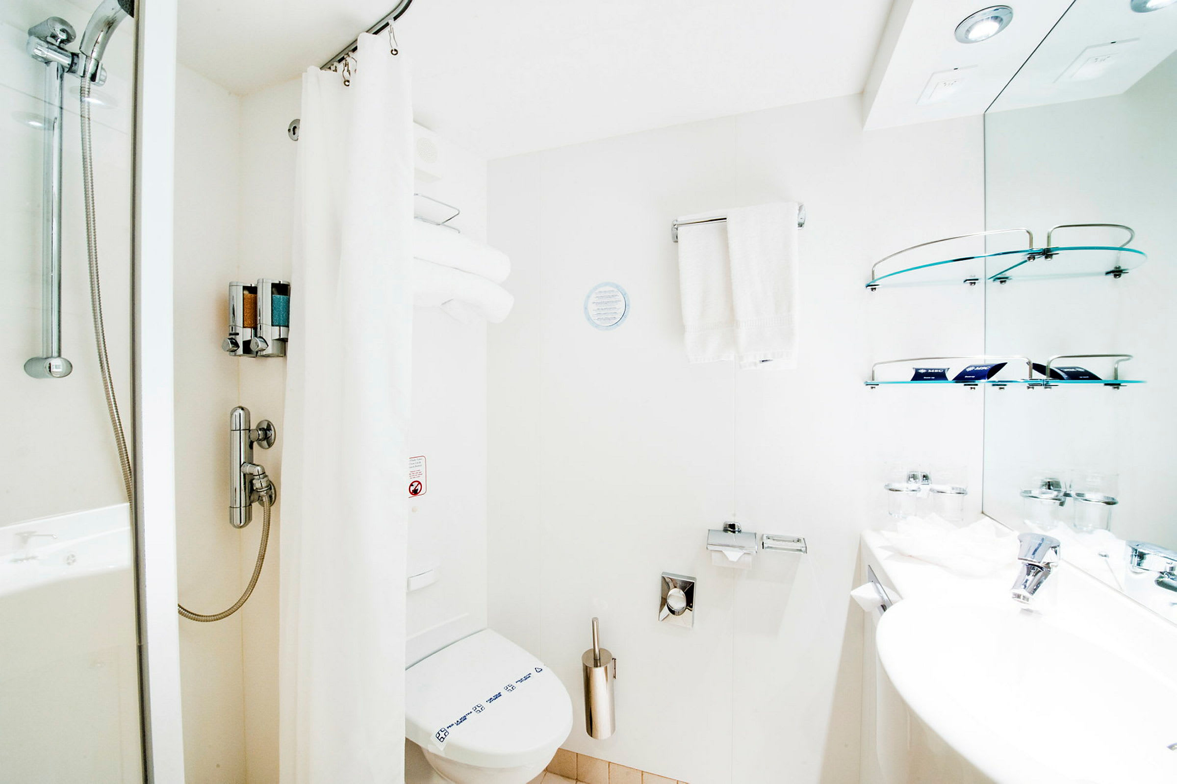 Et lyst badeværelse med bruser, toilet og håndvask. (AI-genereret tekst)