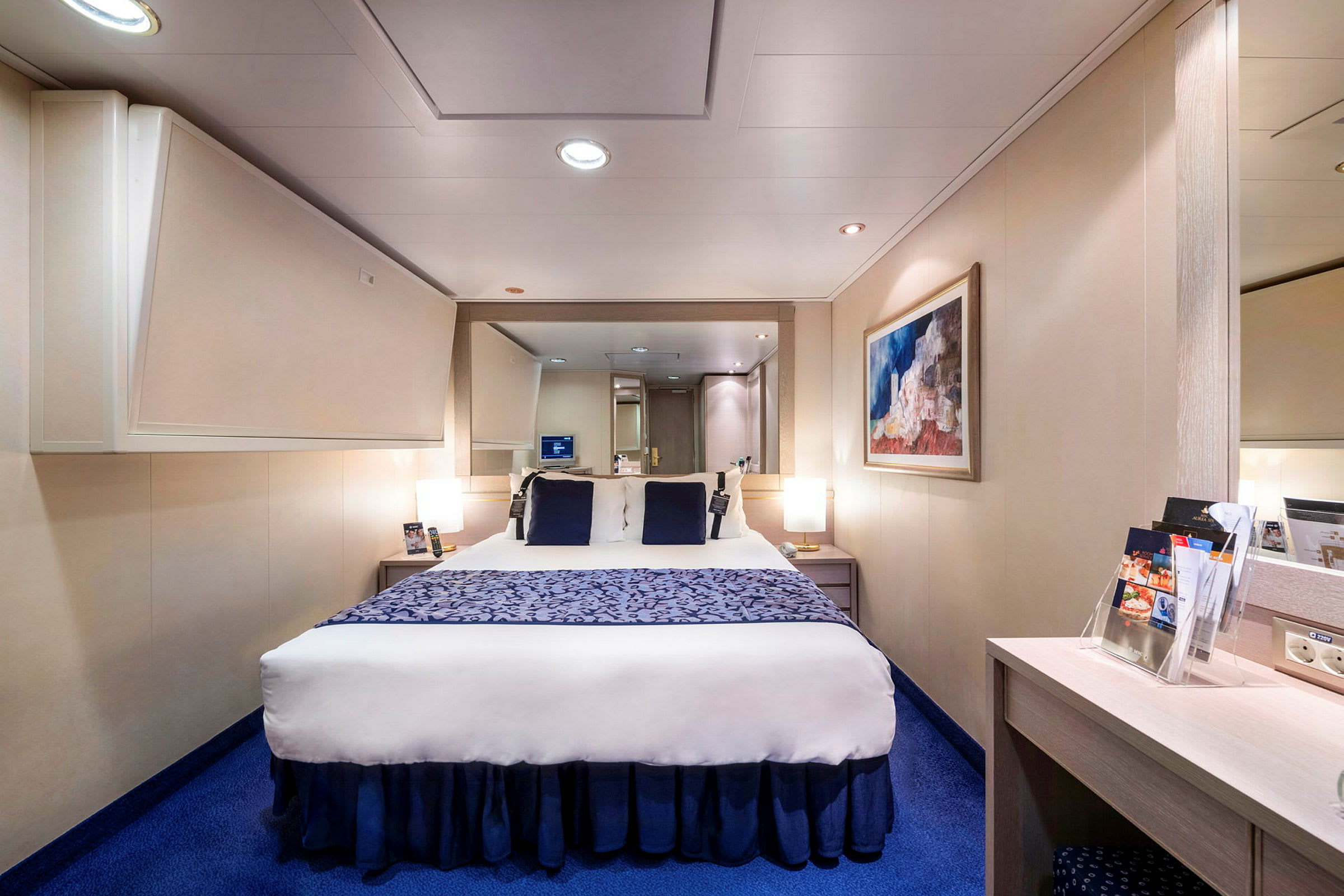 Billede af et moderne hotelværelse med en dobbeltseng, blå tæppe og vægdekoration. (AI-genereret tekst)
