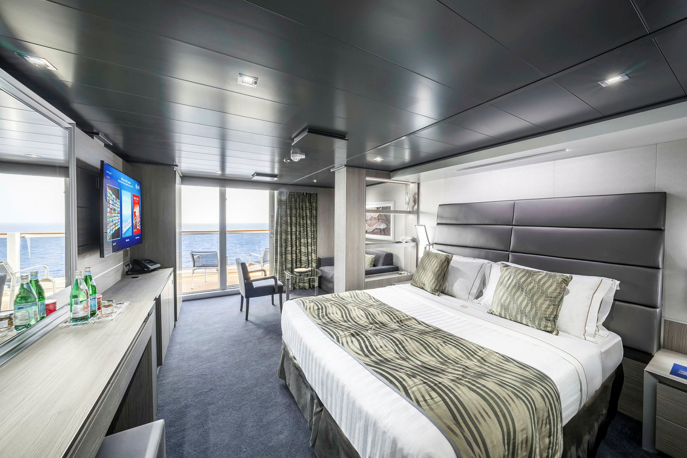 Moderne hotelværelse med stor seng, siddeområde og havudsigt. (AI-genereret tekst)