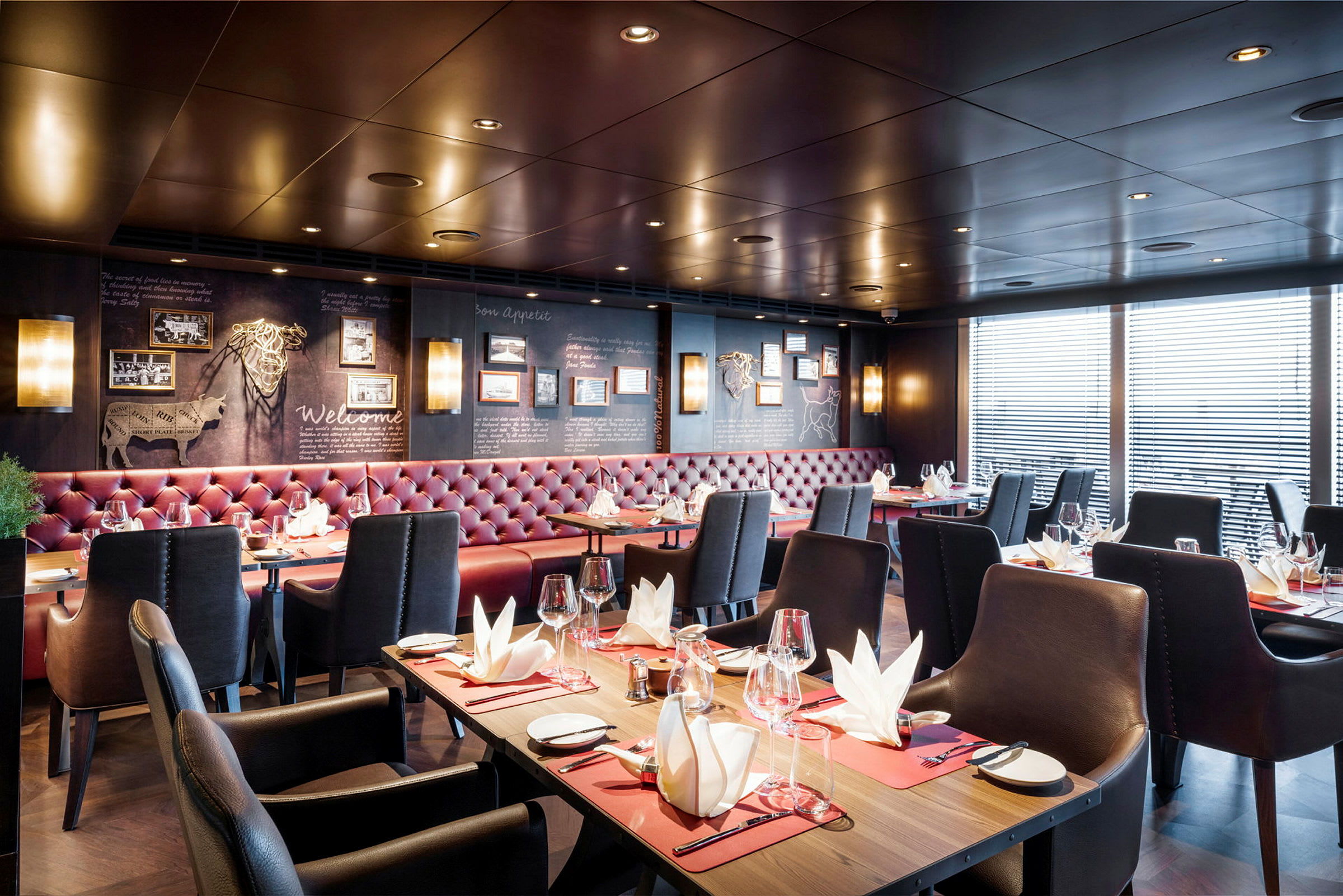 Interiør af en elegant restaurant med dækkede borde og røde polstrede sofaer. (AI-genereret tekst)