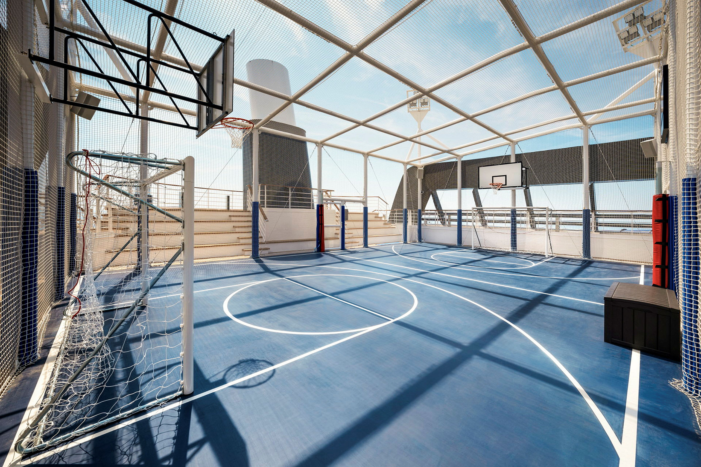 Indhegnet sportsplads med blå overflade og basketballkurve. (AI-genereret tekst)