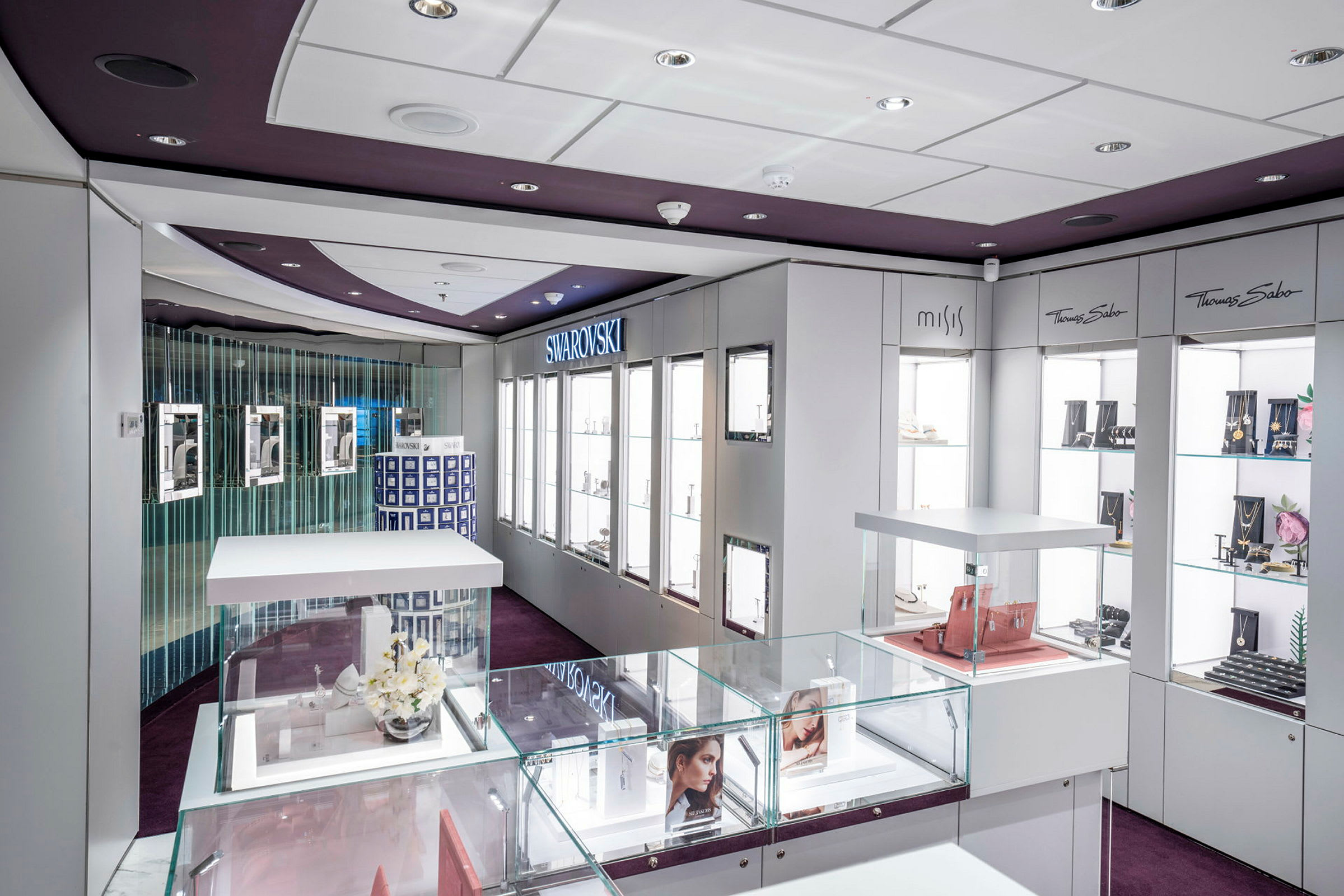 Et moderne smykkebutikinteriør med glasmontrer og mærker som Swarovski og Thomas Sabo. (AI-genereret tekst)