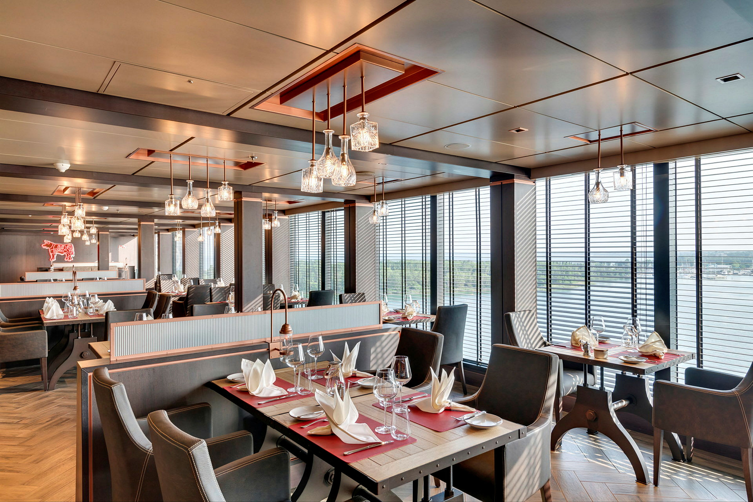 Restaurant med borde, stole og servietter, store vinduer med udsigt. (AI-genereret tekst)