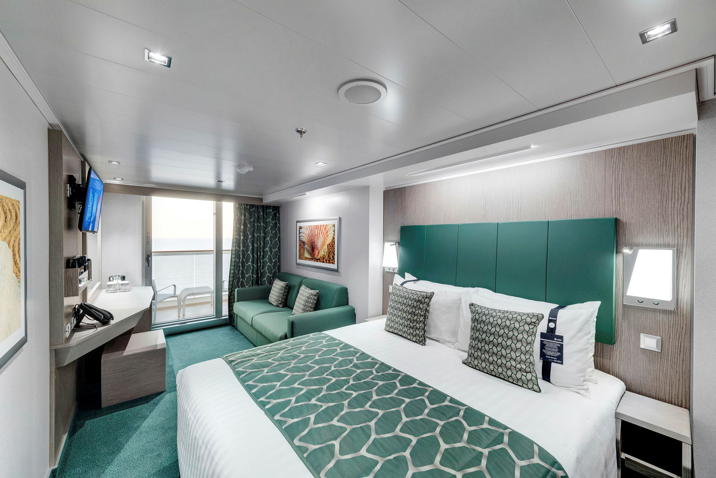 Et moderne hotelværelse med seng, sofa og altan med udsigt. (AI-genereret tekst)