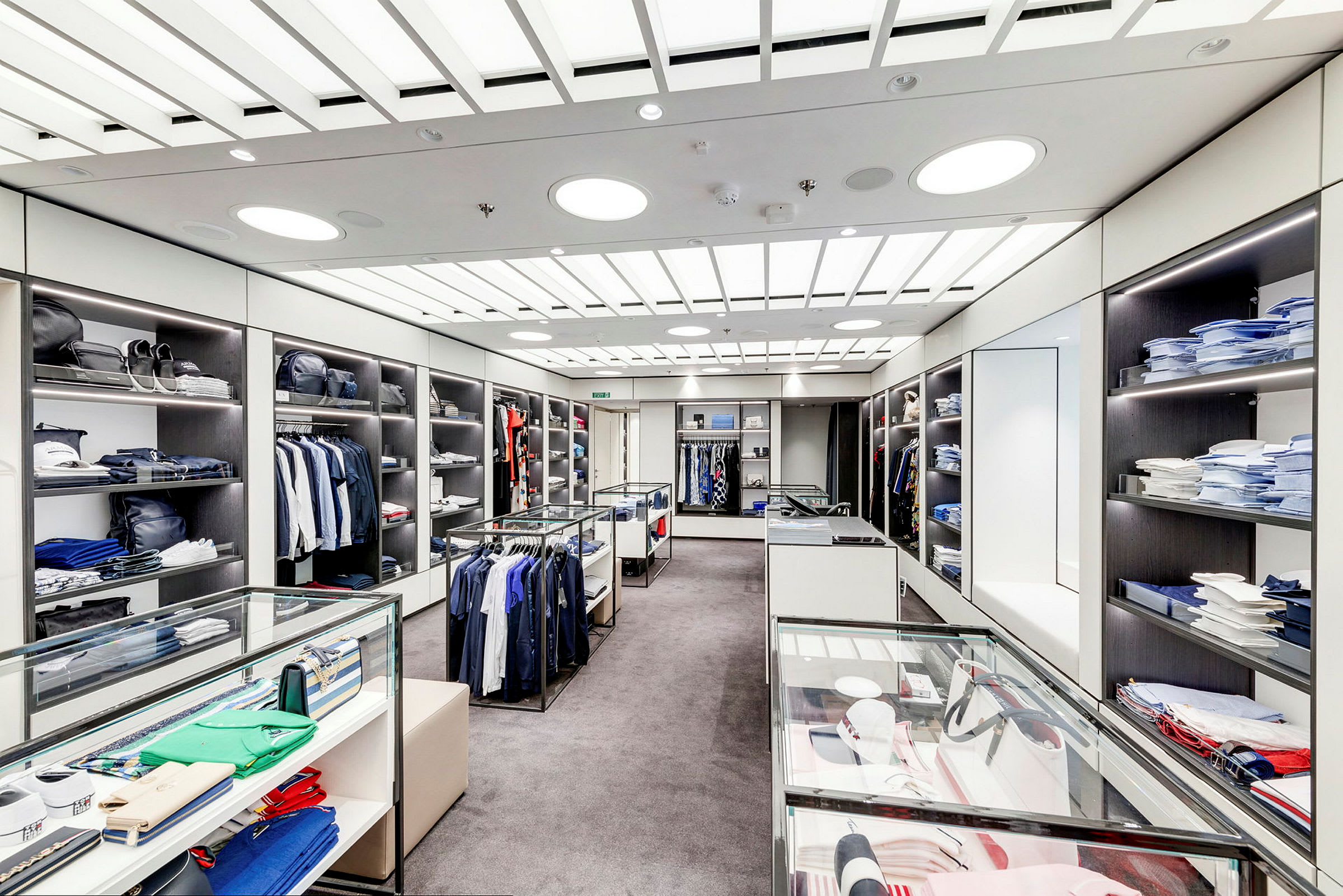 En indrettet tøjbutik med hylder, glasmontrer og tøj. (AI-genereret tekst)