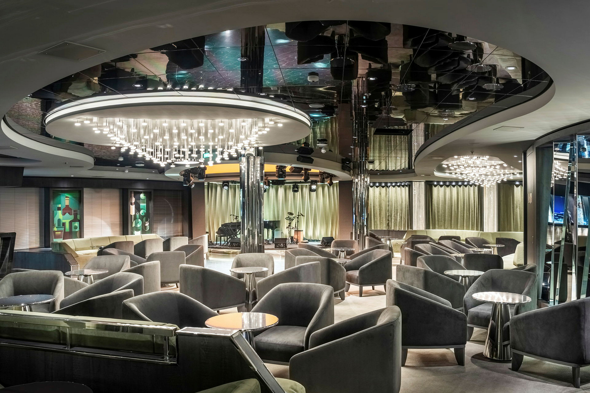 Lounge med komfortable stole, små borde og hængende lysekroner. (AI-genereret tekst)