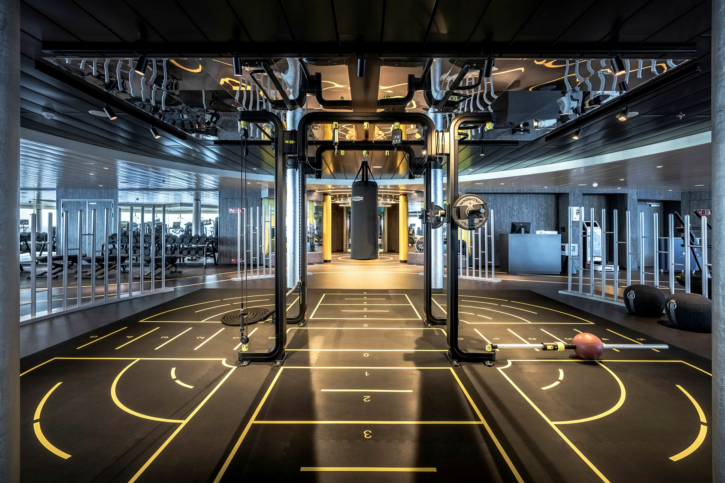 Et moderne fitnesscenter med træningsudstyr og markerede områder på gulvet. (AI-genereret tekst)