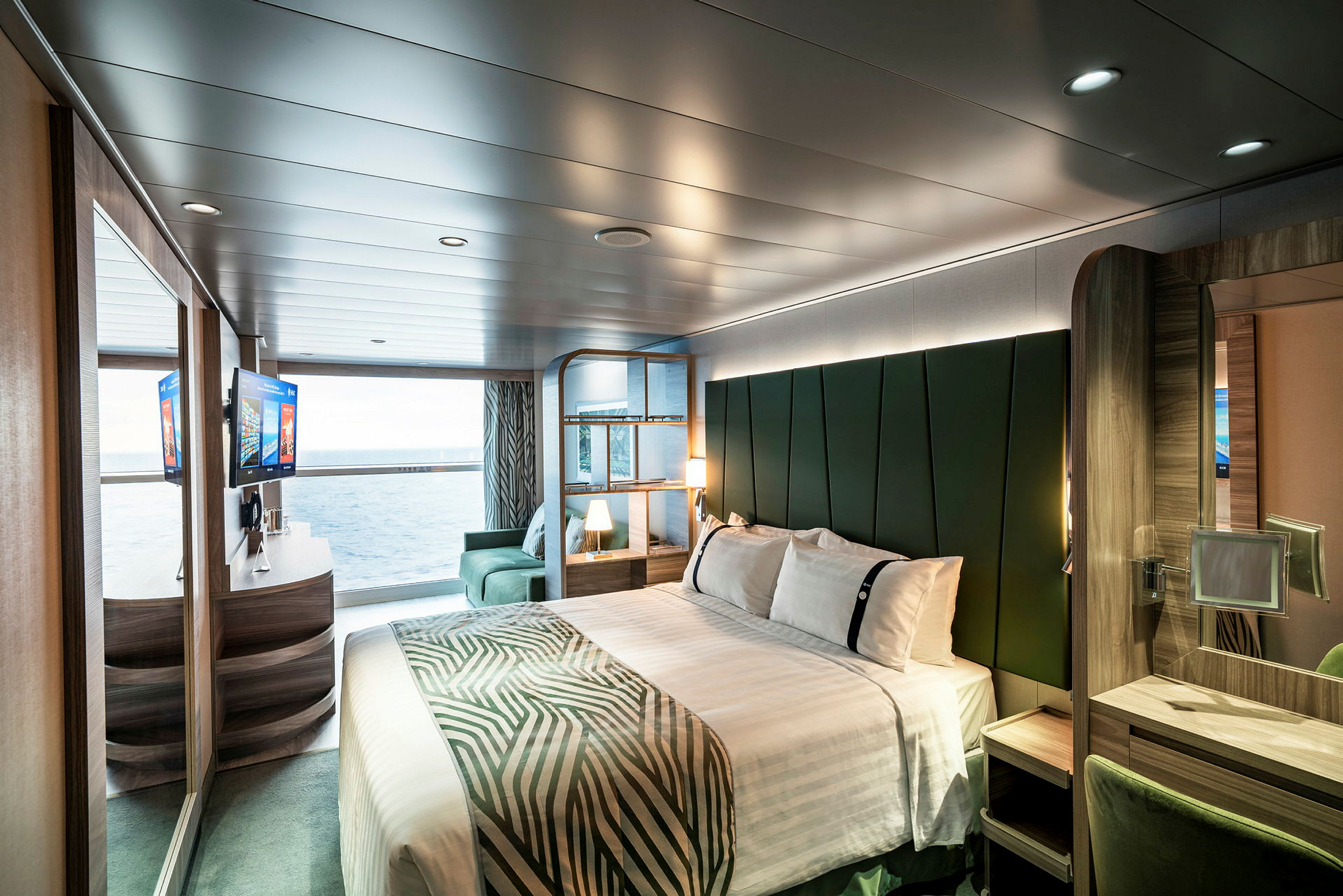 Interiør af et moderne hotelværelse med seng, siddepladser og havudsigt. (AI-genereret tekst)