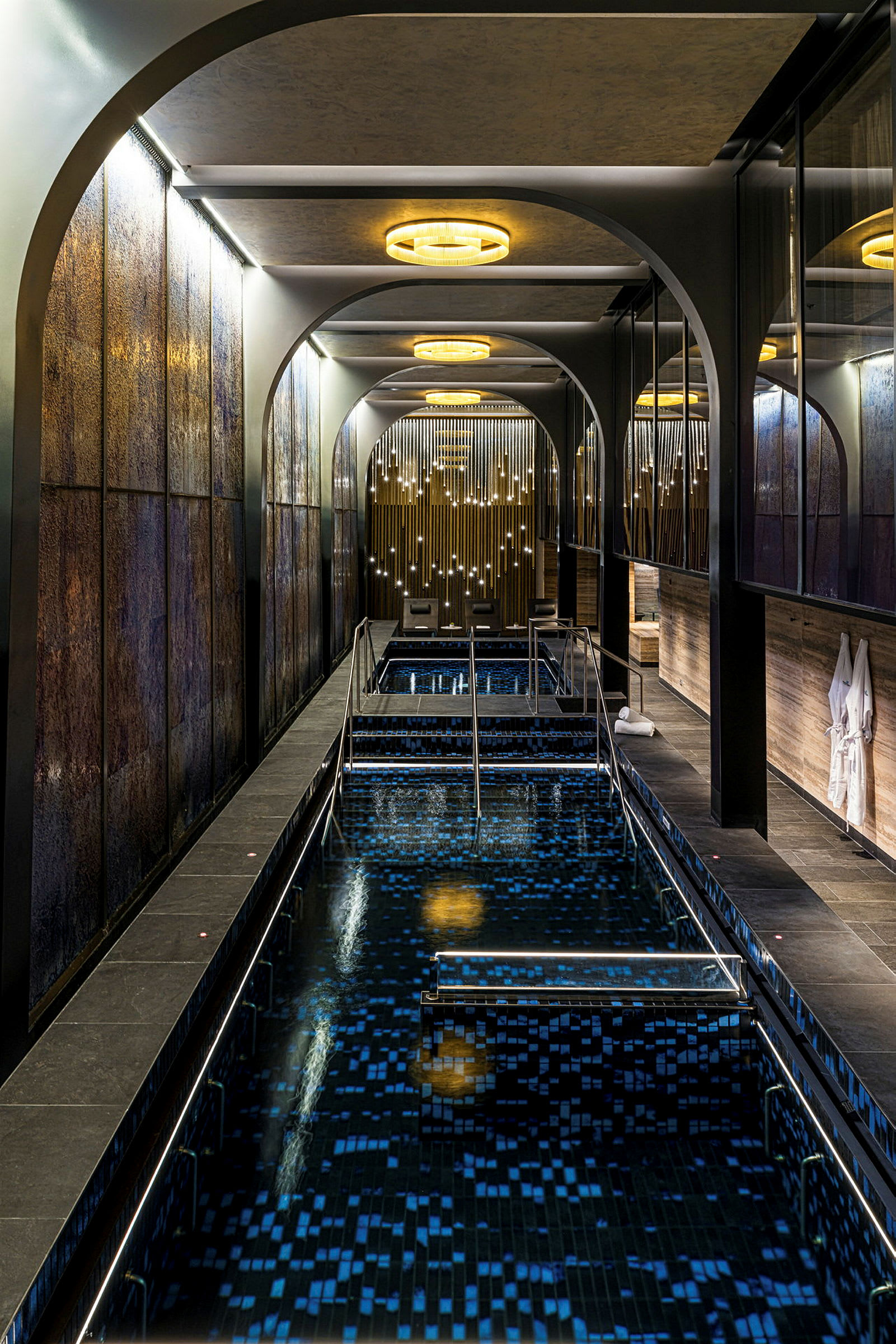 En indendørs pool med moderne, arkitektonisk designede omgivelser og blødt lys fra dekorationer. (AI-genereret tekst)