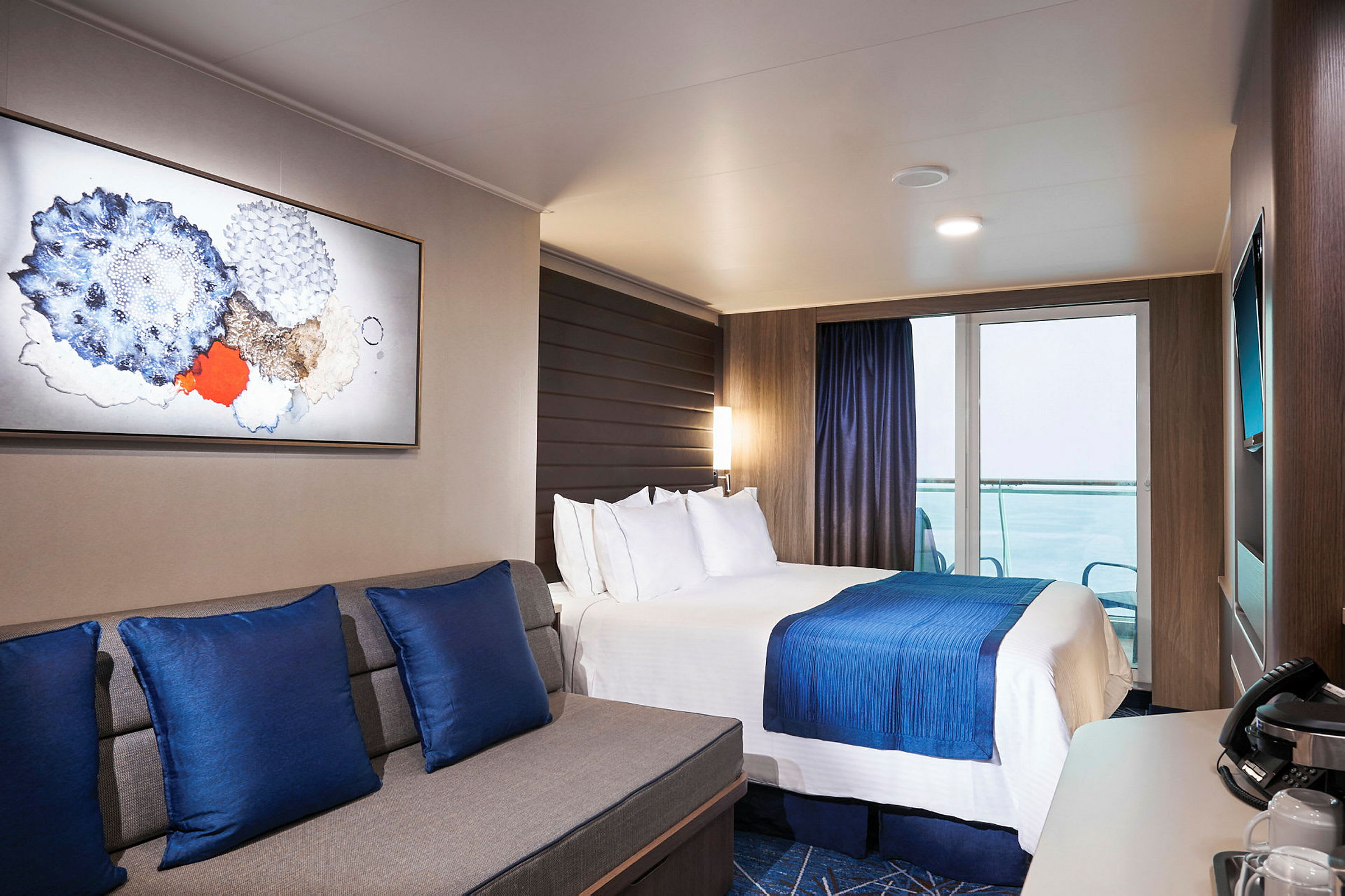 Et moderne hotelværelse med en dobbeltseng, blå dekorative detaljer og en siddegruppe. (AI-genereret tekst)