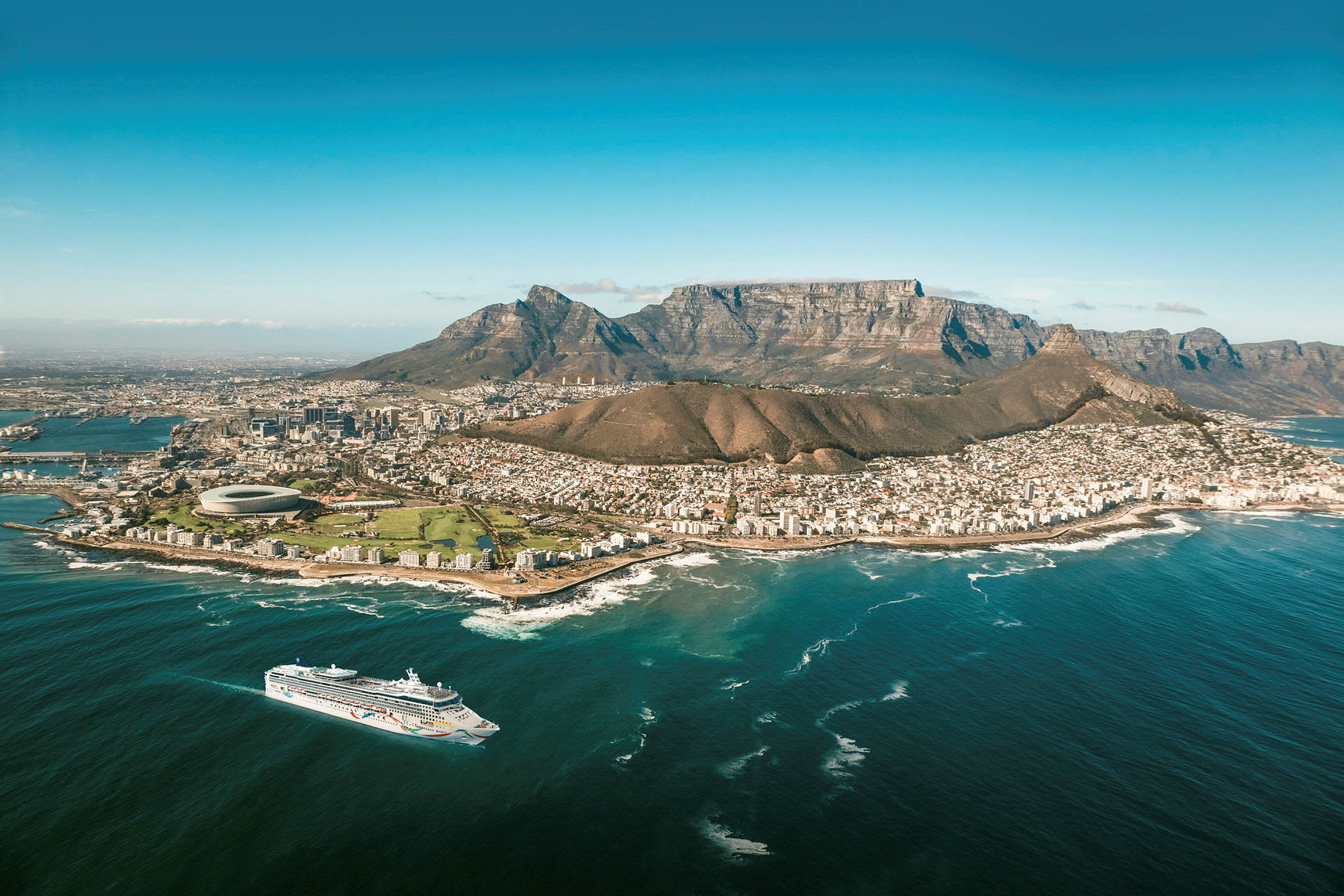 En udsigt over Cape Town med Taffelbjerget i baggrunden og et krydstogtskib på havet. (AI-genereret tekst)