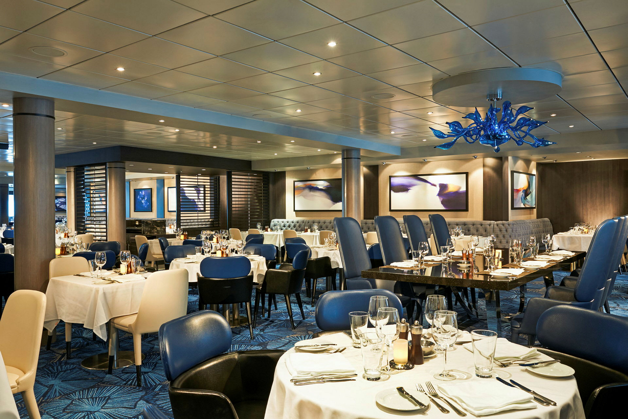 En elegant restaurant med dækkede borde og blå stole. (AI-genereret tekst)