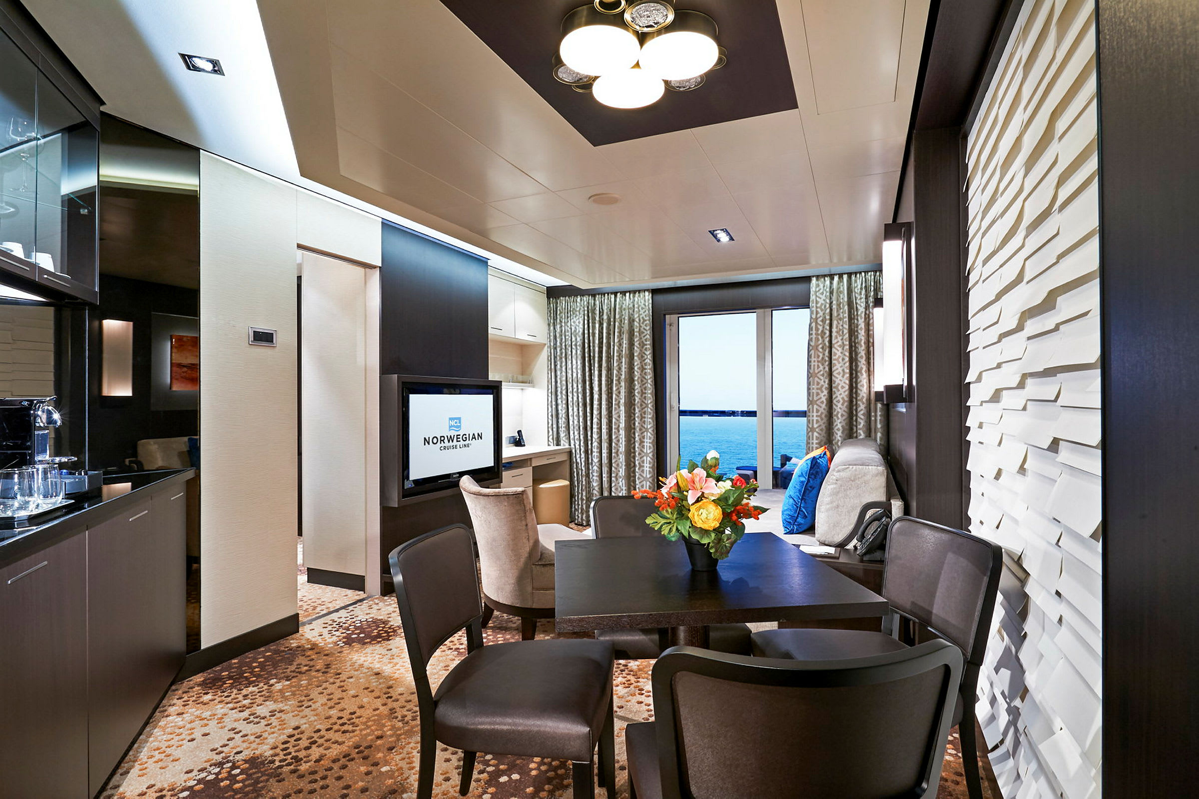 Indretning af en moderne hotelsuite med et bord, stole og udsigt over havet. (AI-genereret tekst)