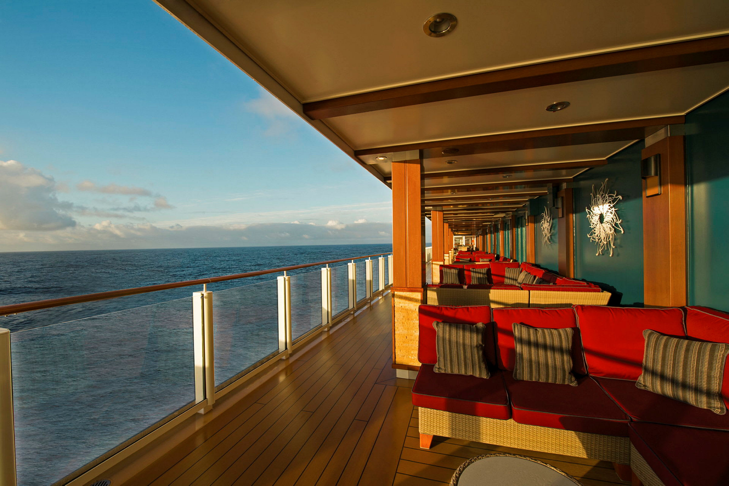 En overdækket terrasse med røde siddepladser og udsigt over havet. (AI-genereret tekst)