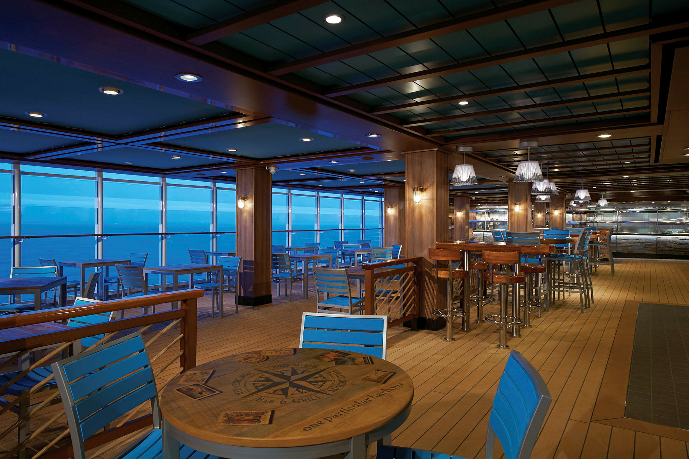 Restaurant med blå stole og træborde, havudsigt i baggrunden. (AI-genereret tekst)