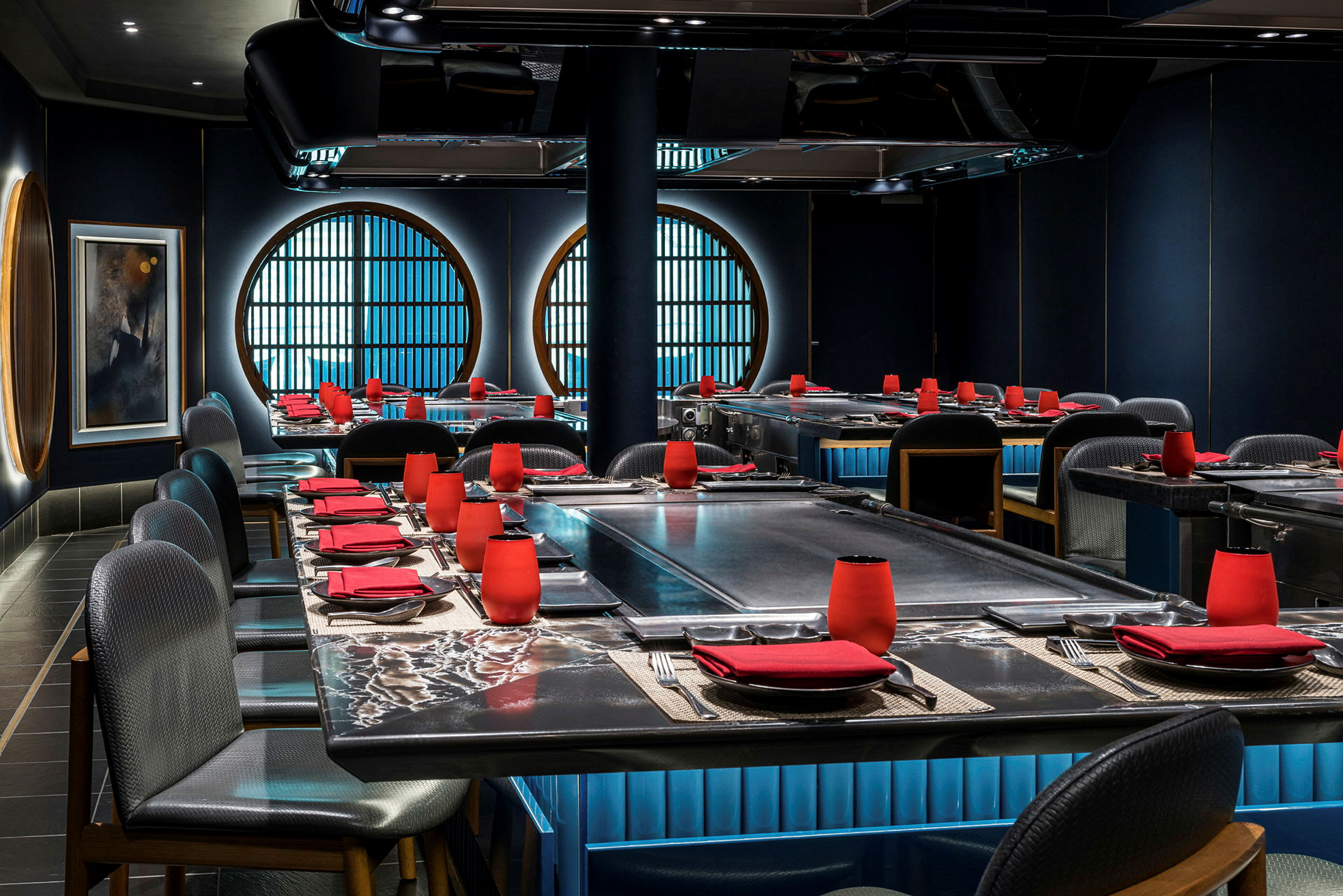 Billede af en stilfuld restaurant med mørk indretning, røde detaljer og store cirkulære vinduer. (AI-genereret tekst)