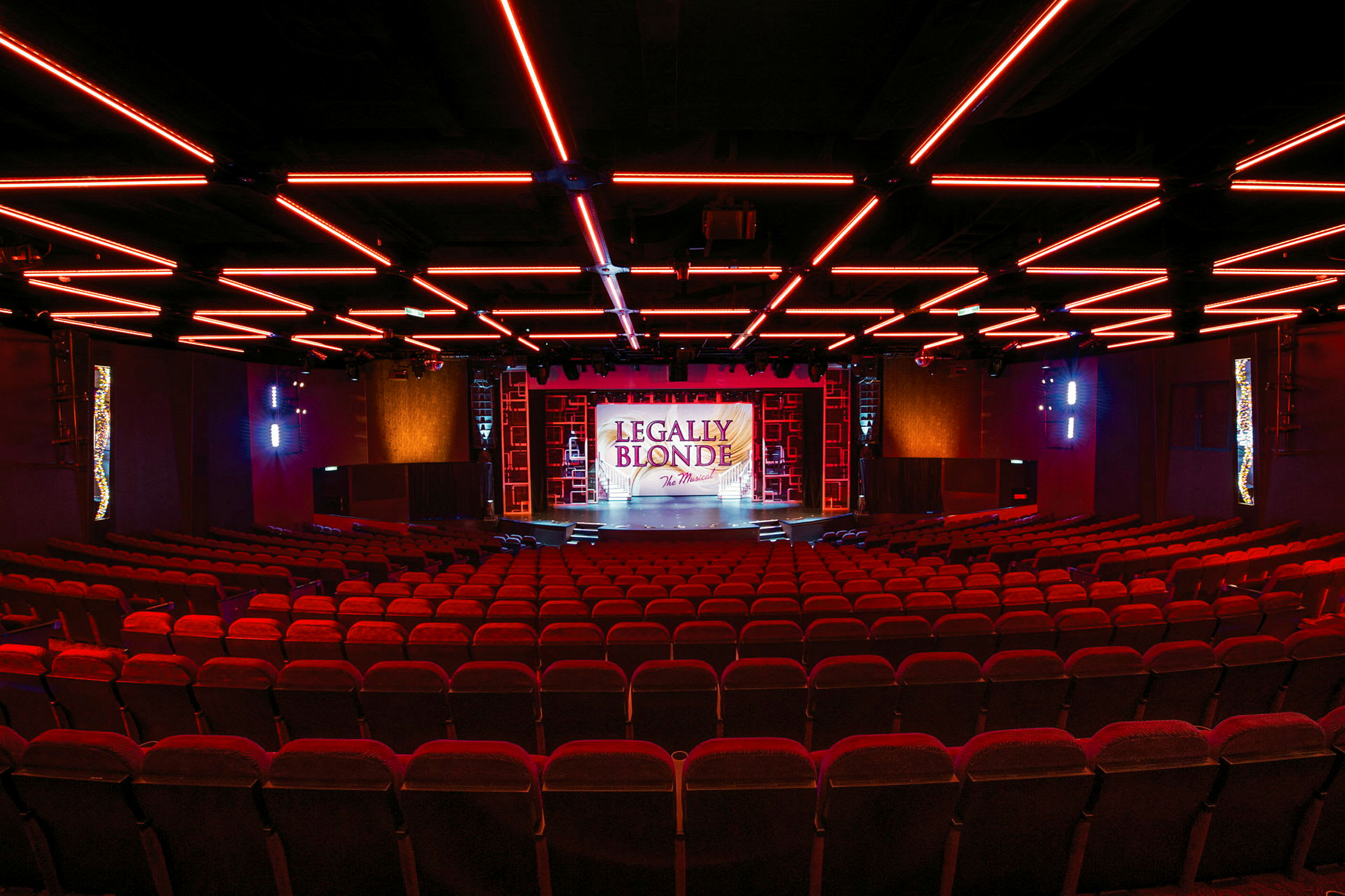 En teater med røde sæder og en oplyst scene med teksten 'Legally Blonde'. (AI-genereret tekst)