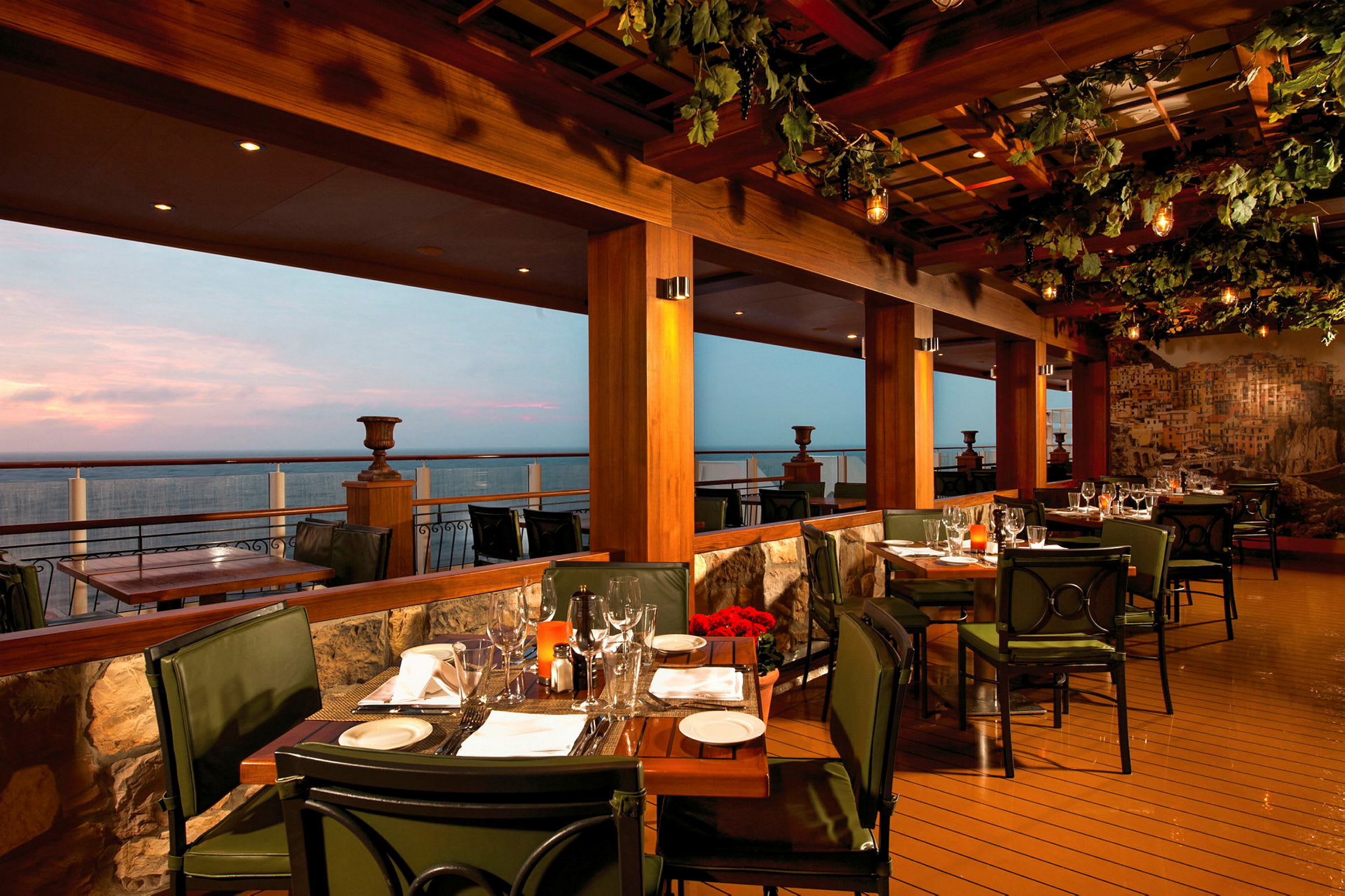 En restaurant med borde og stole på en terrasse ud mod havet ved skumringstid. (AI-genereret tekst)