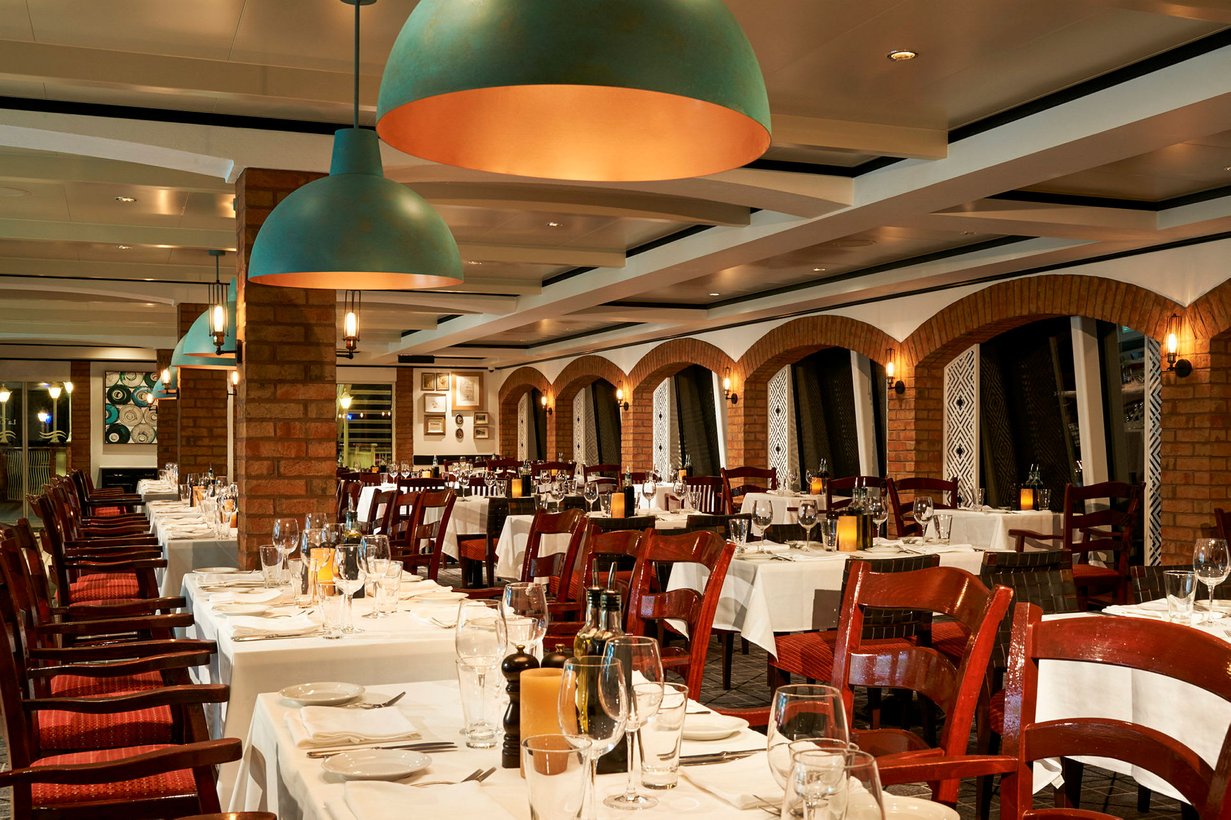 En elegant restaurant med borde dækket med hvide duge og glas, omgivet af murstensvægge og dekorative buer. (AI-genereret tekst)