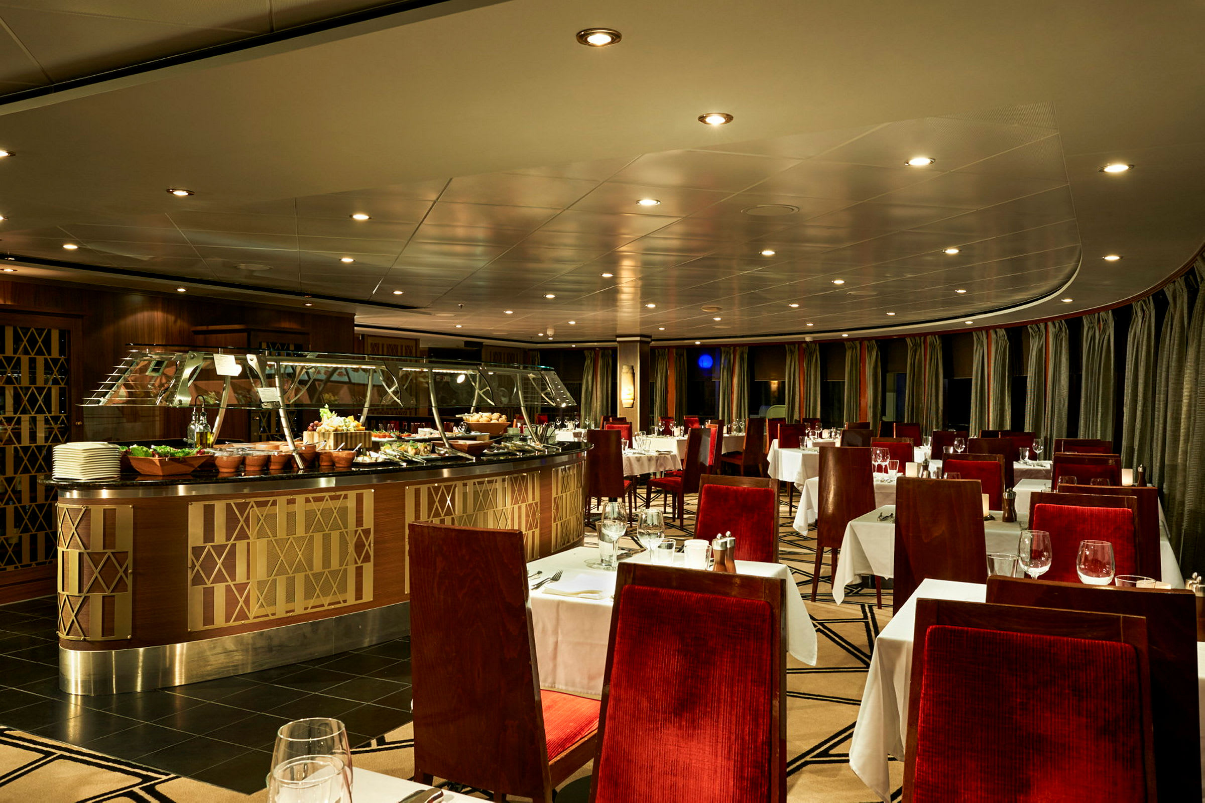 Interiør af en elegant restaurant med røde polstrede stole og hvide duge. En buffet med mad er placeret centralt. (AI-genereret tekst)