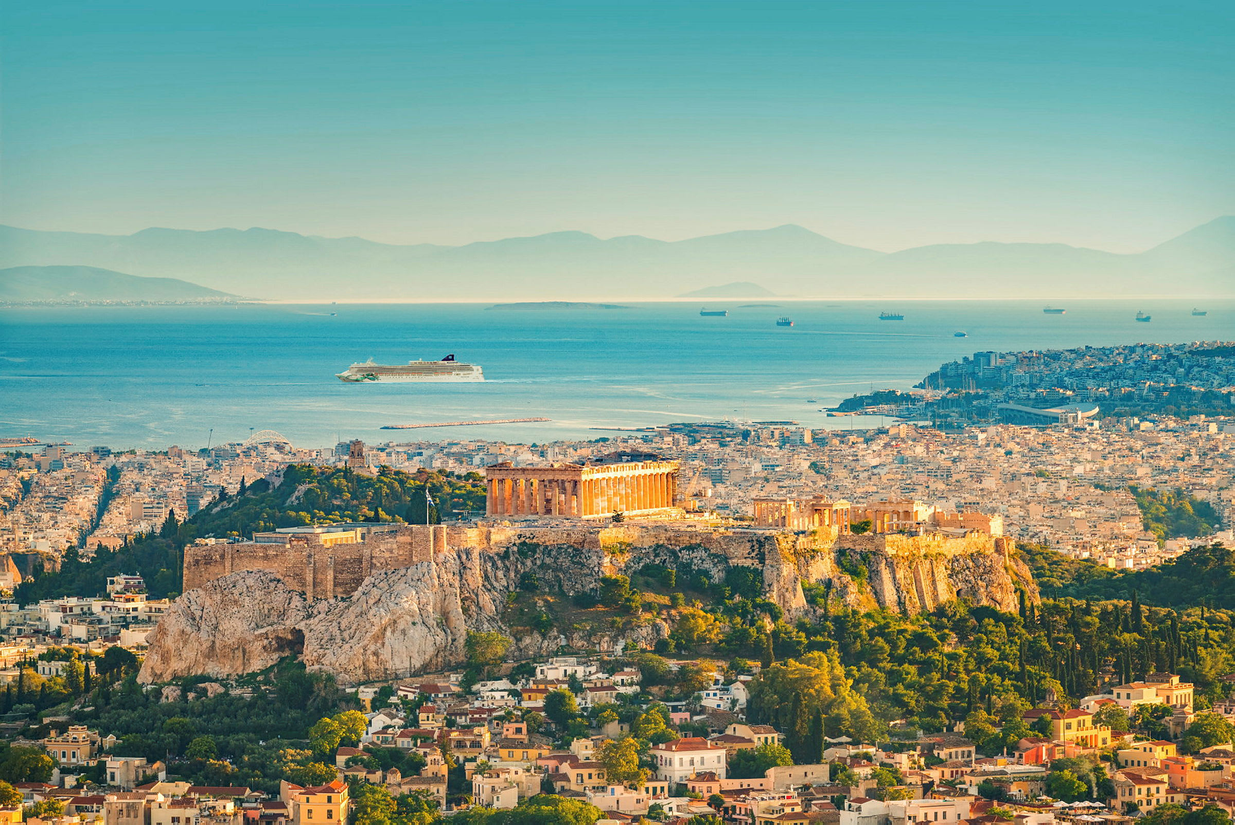 Billede af Akropolis i Athen med Parthenon på en høj over byen og havet i baggrunden. (AI-genereret tekst)