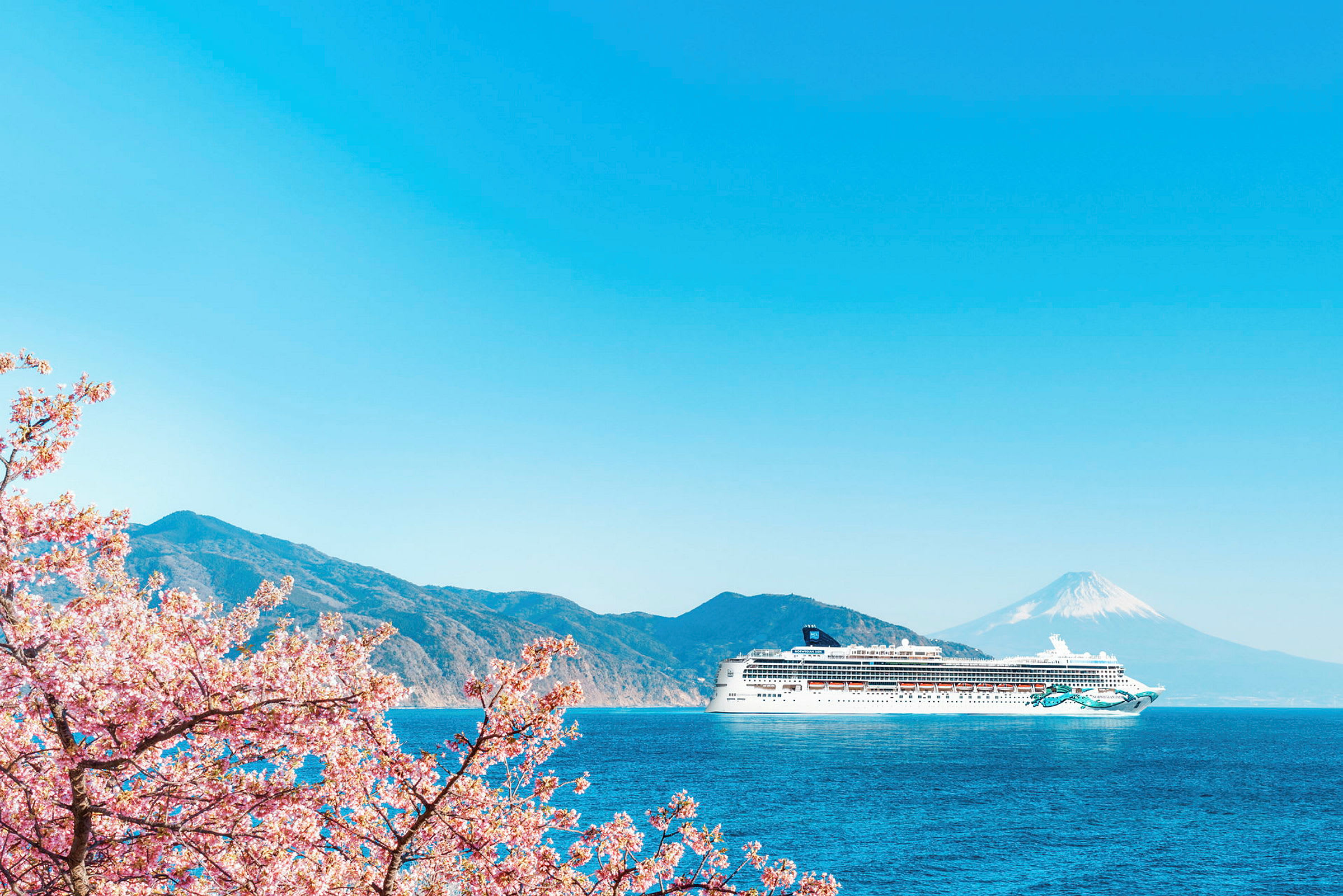 Et krydstogtskib på en blå havudsigt med bjerge og Mount Fuji i baggrunden, samt kirsebærblomster i forgrunden. (AI-genereret tekst)