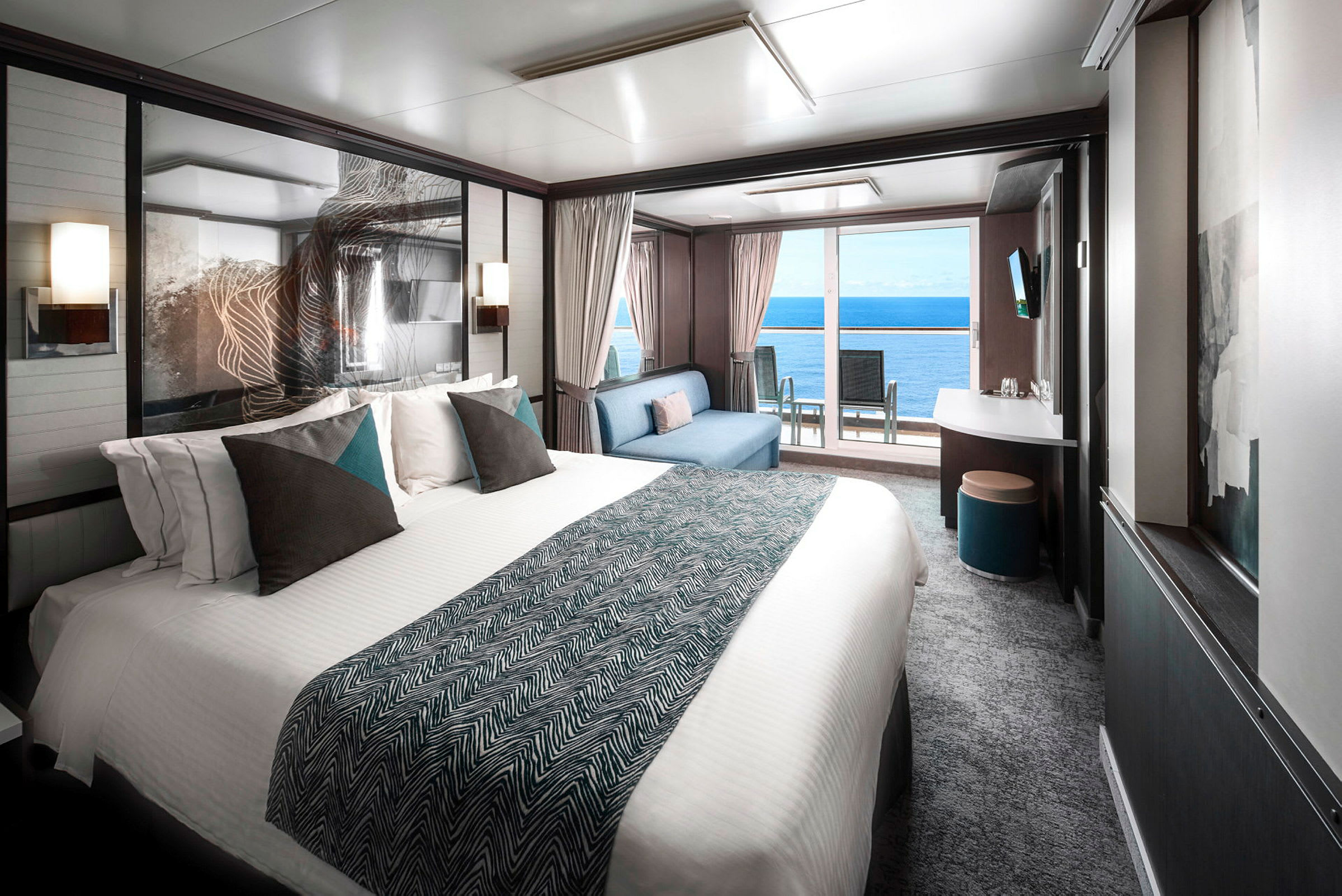 Billede af et moderne hotelværelse med en stor seng, en siddegruppe og udsigt over havet gennem store vinduer. (AI-genereret tekst)