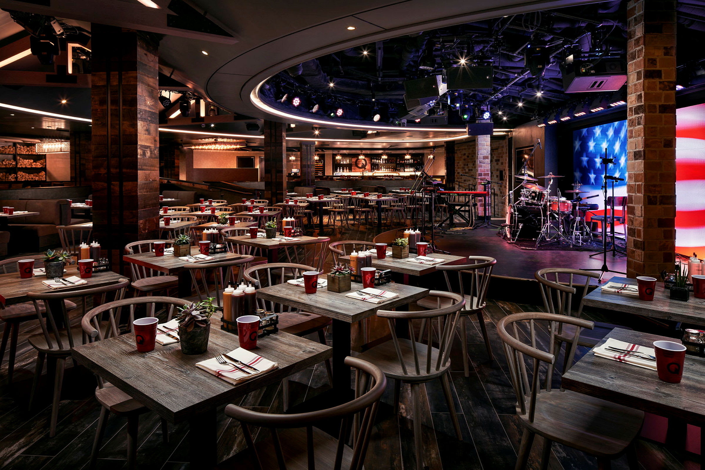 En restaurant med borde og stole samt en scene med musikudstyr. (AI-genereret tekst)