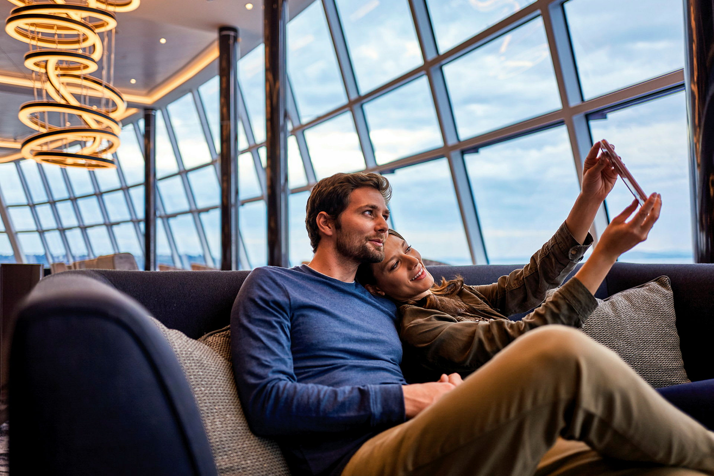 En moderne lounge med store vinduer og hængende lysekroner. (AI-genereret tekst)