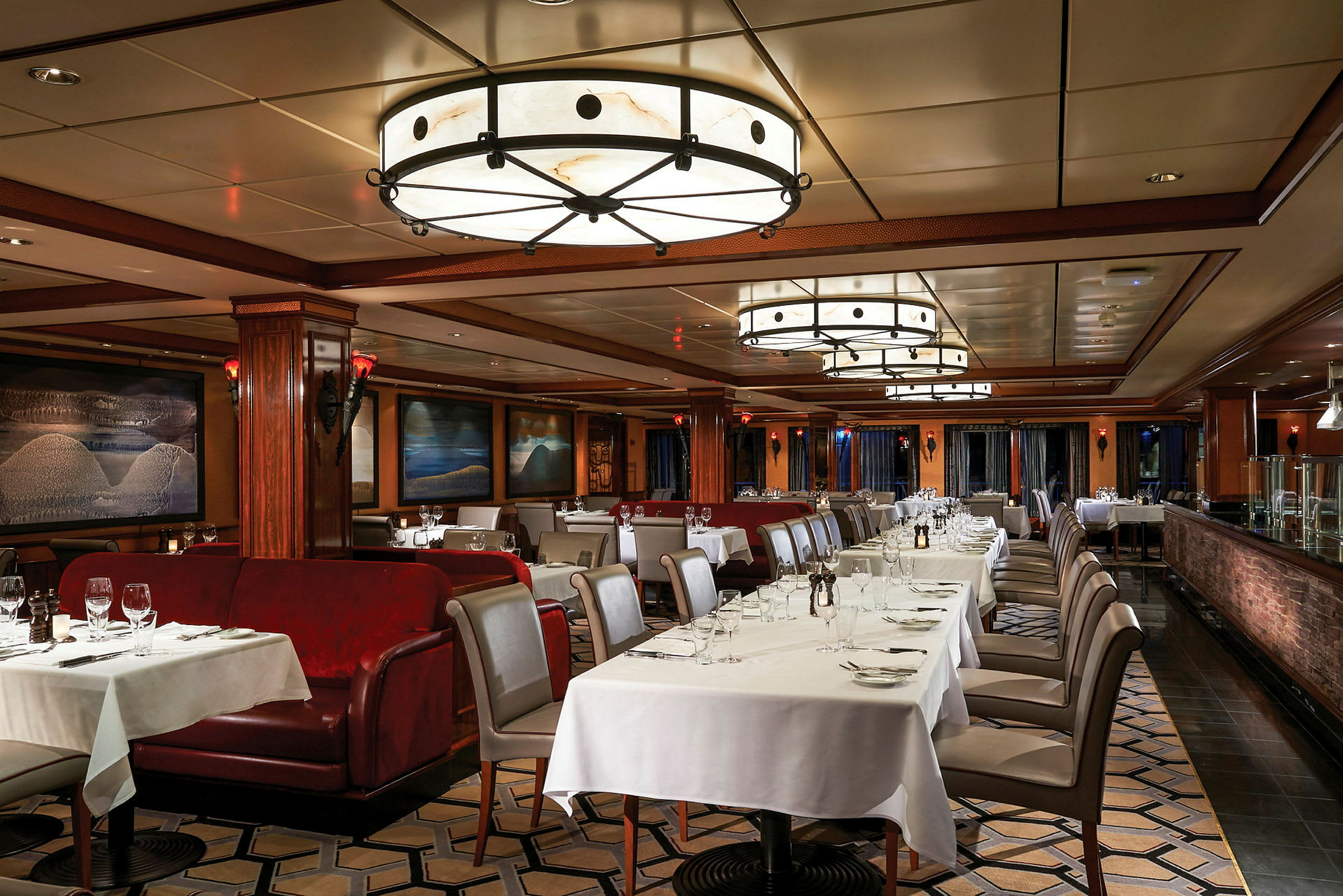 Elegant restaurant med borde og stole dækket med hvide duge og røde polstrede sofaer. (AI-genereret tekst)