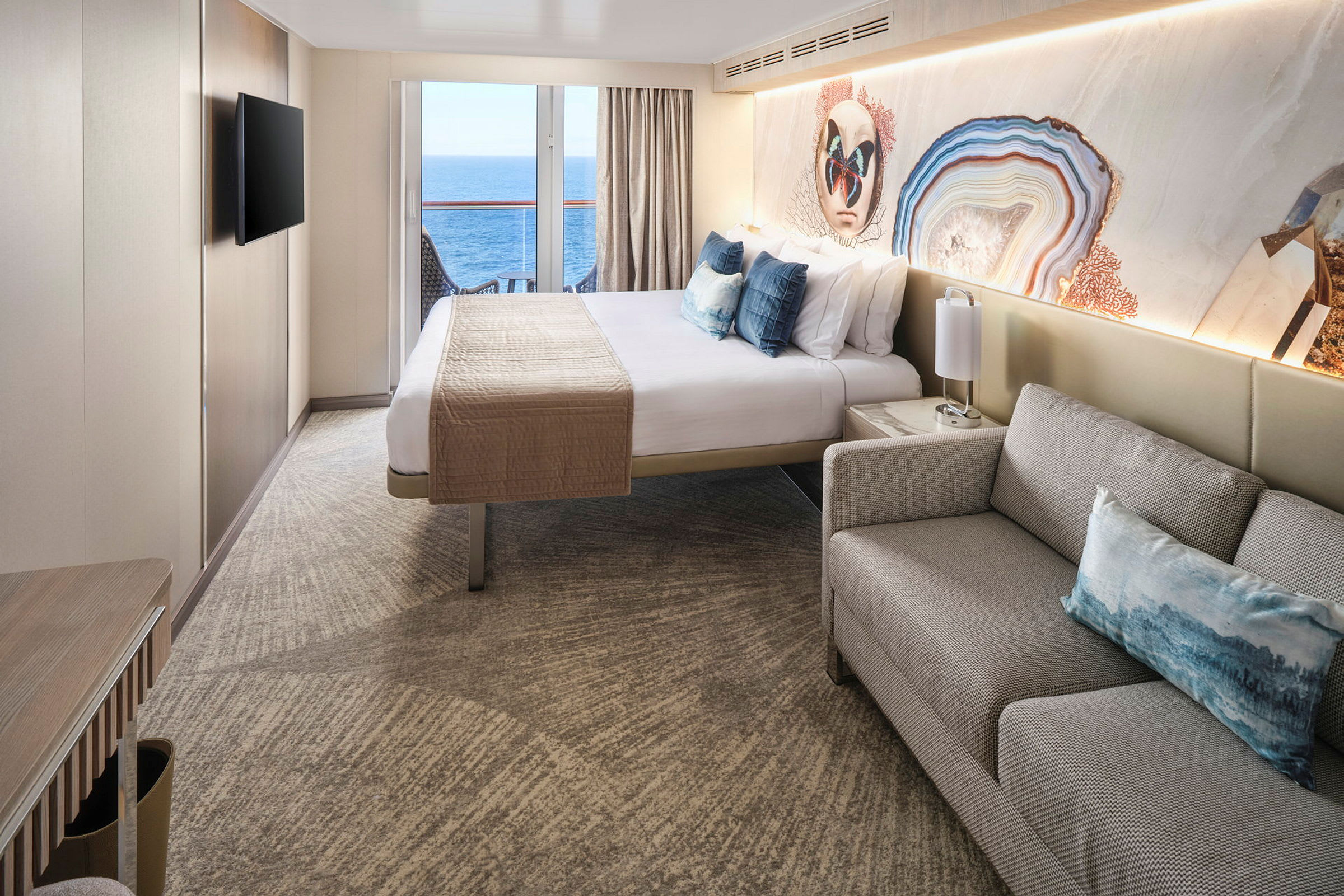 Interiørbillede af et hotelværelse med en dobbeltseng, sofa og en balkon med udsigt over havet. (AI-genereret tekst)