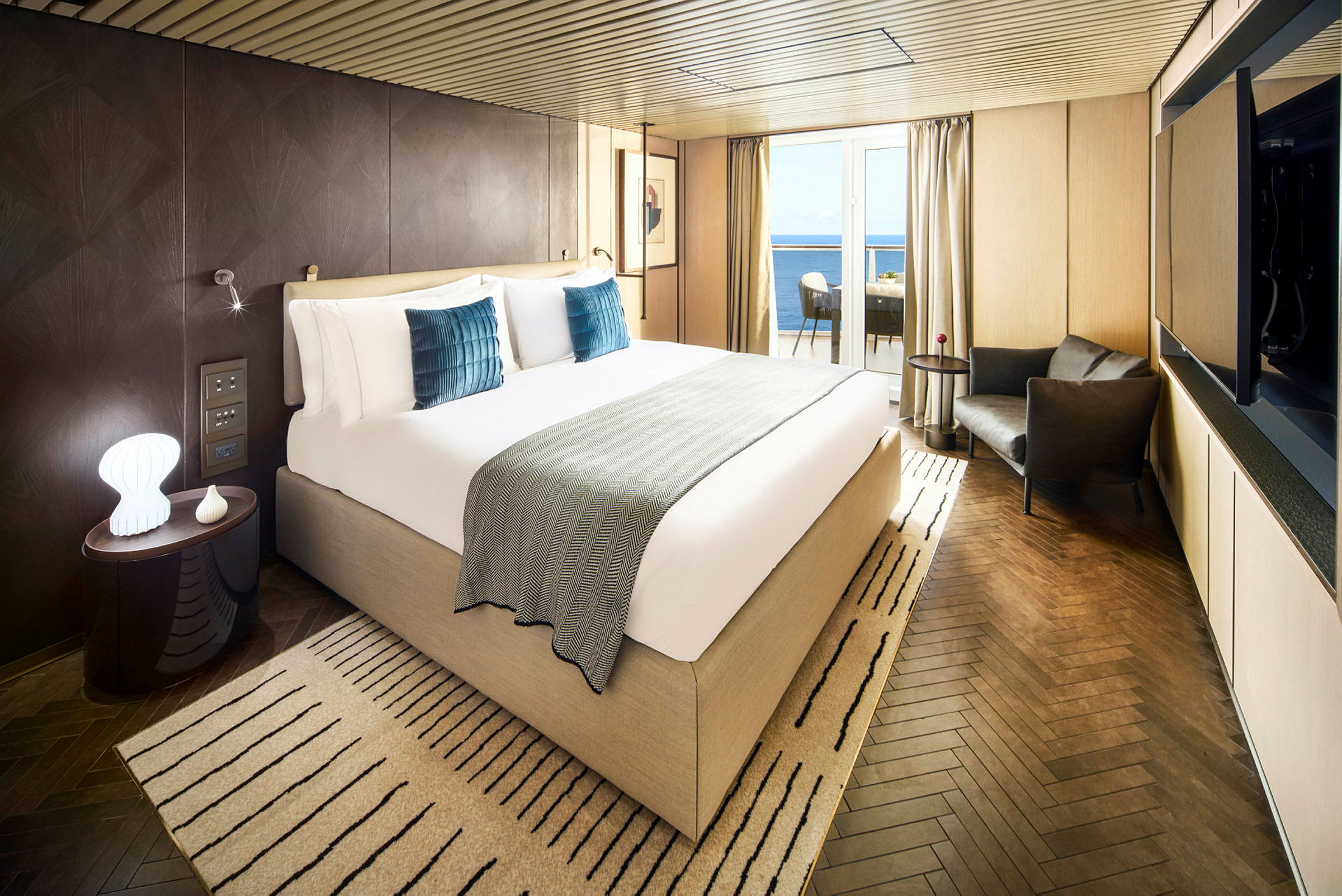 Hotelværelse med stor seng, siddeområde og altan med udsigt over havet. (AI-genereret tekst)