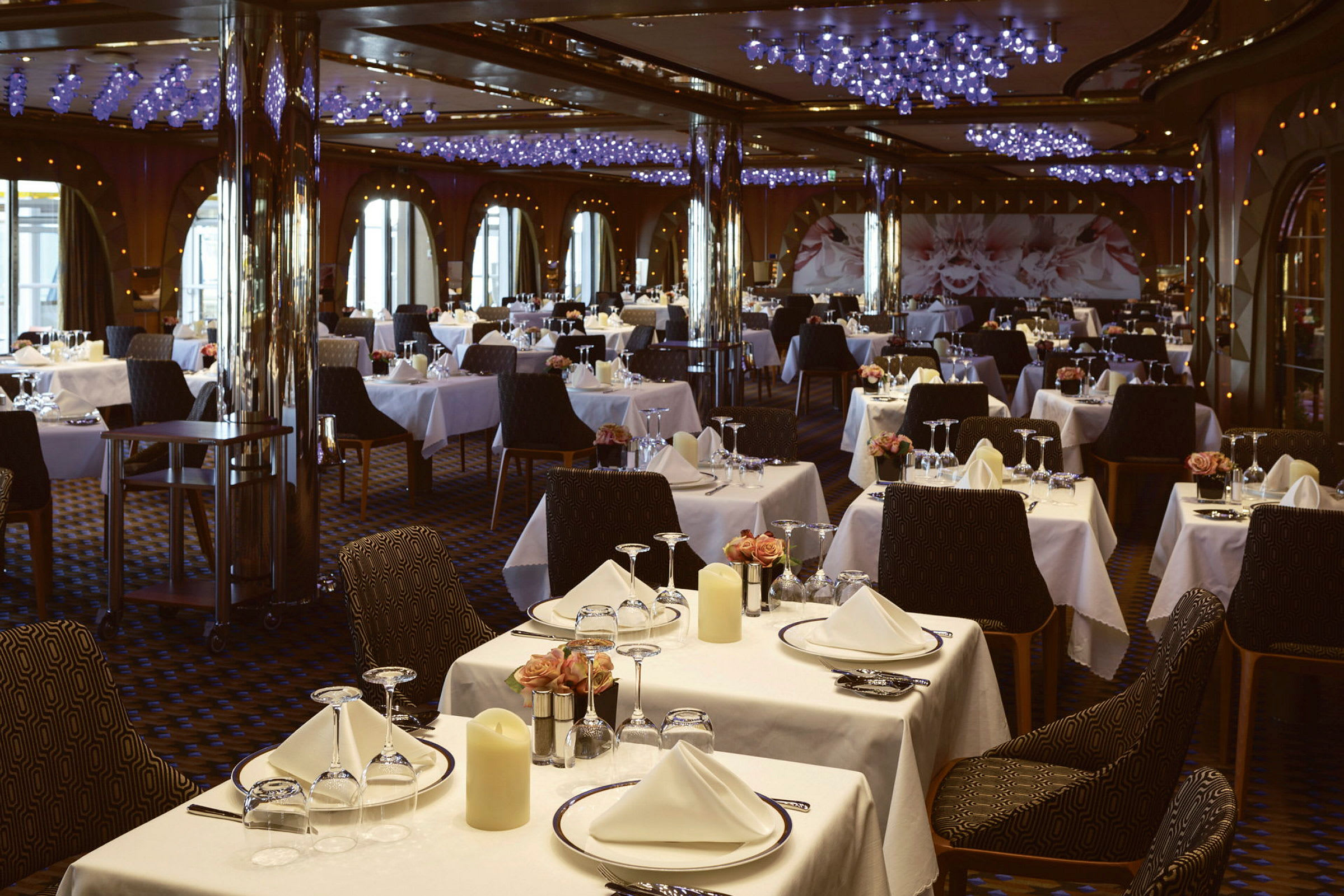 En restaurant med mange borde opstillet med hvide duge, glas og porcelæn. (AI-genereret tekst)