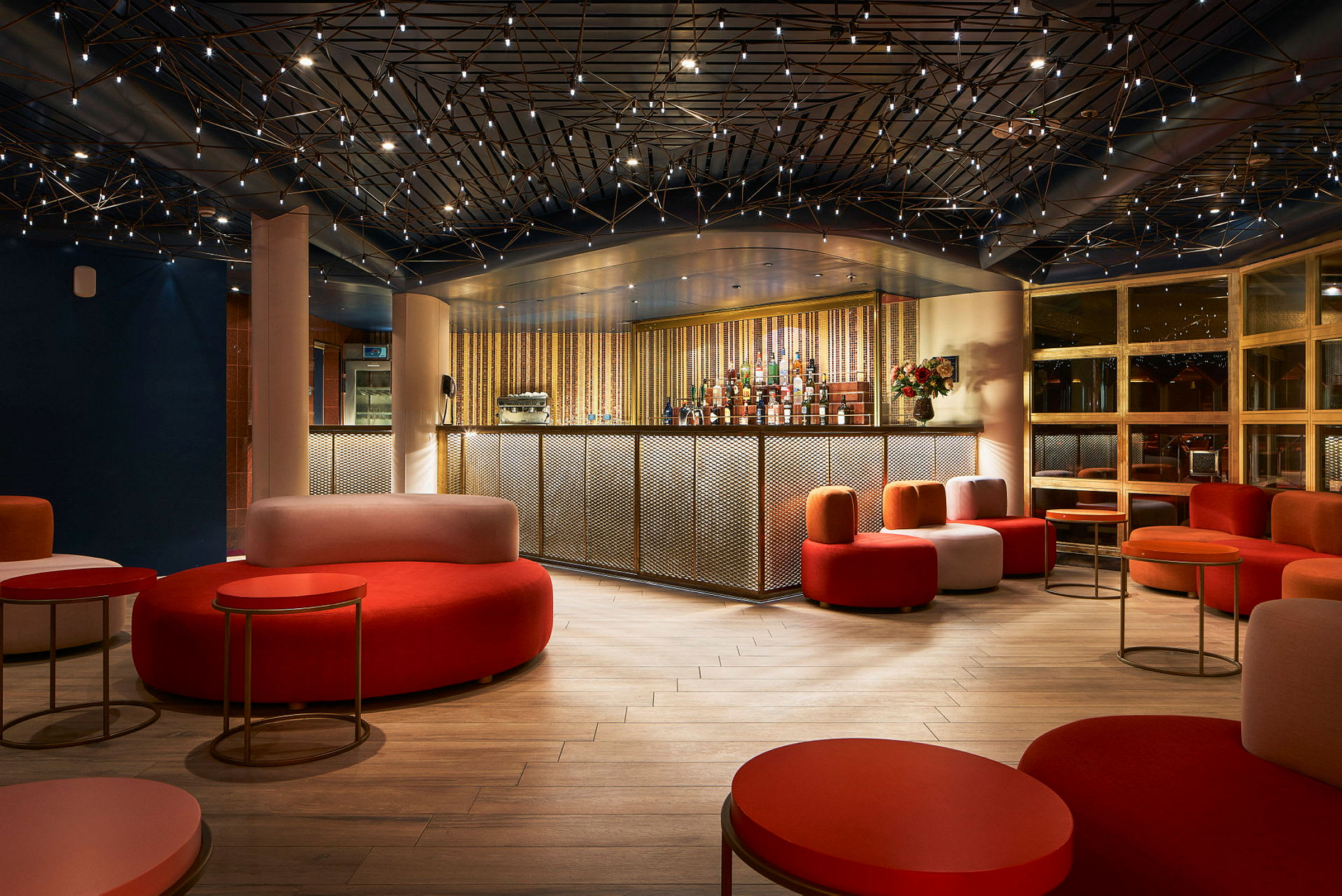 En moderne bar med farverige siddepladser og en stilfuld loftdesign. (AI-genereret tekst)