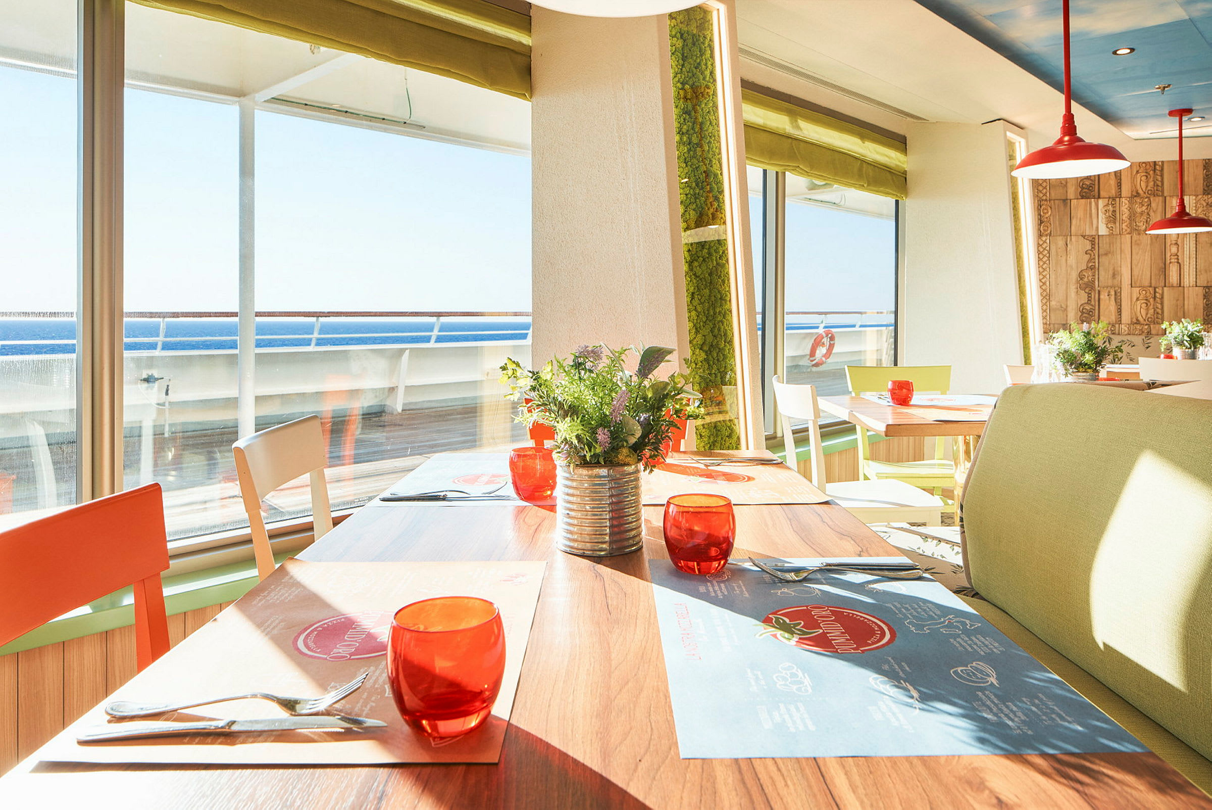 Solrig restaurant med borde, stole og udsigt til havet. (AI-genereret tekst)